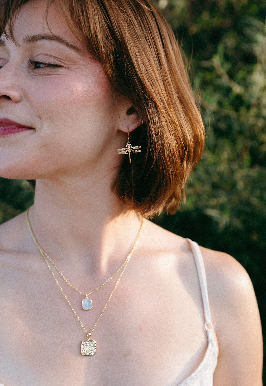 Woman wearing gold dragonfly earrings, dainty nature inspired jewelry styling