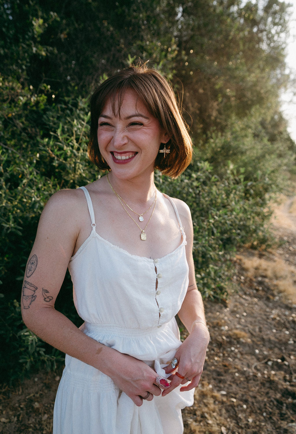 Woman wearing gold dragonfly earrings in nature, feminine everyday jewelry look