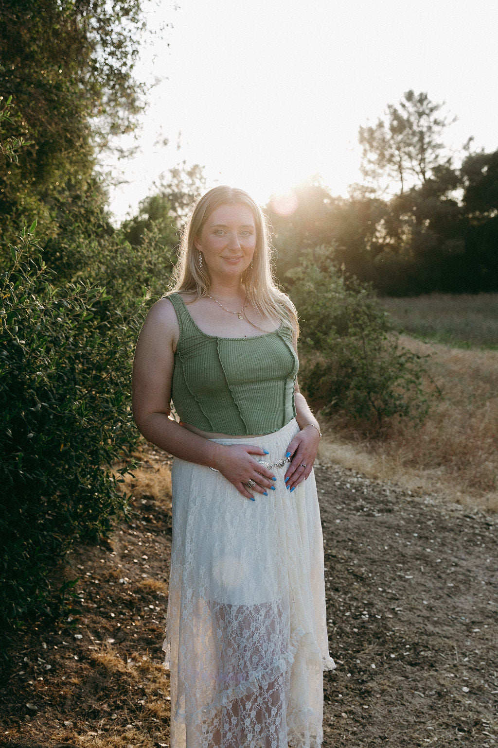 Woman wearing delicate leaf drop earrings outdoors in nature, boho feminine jewelry styling