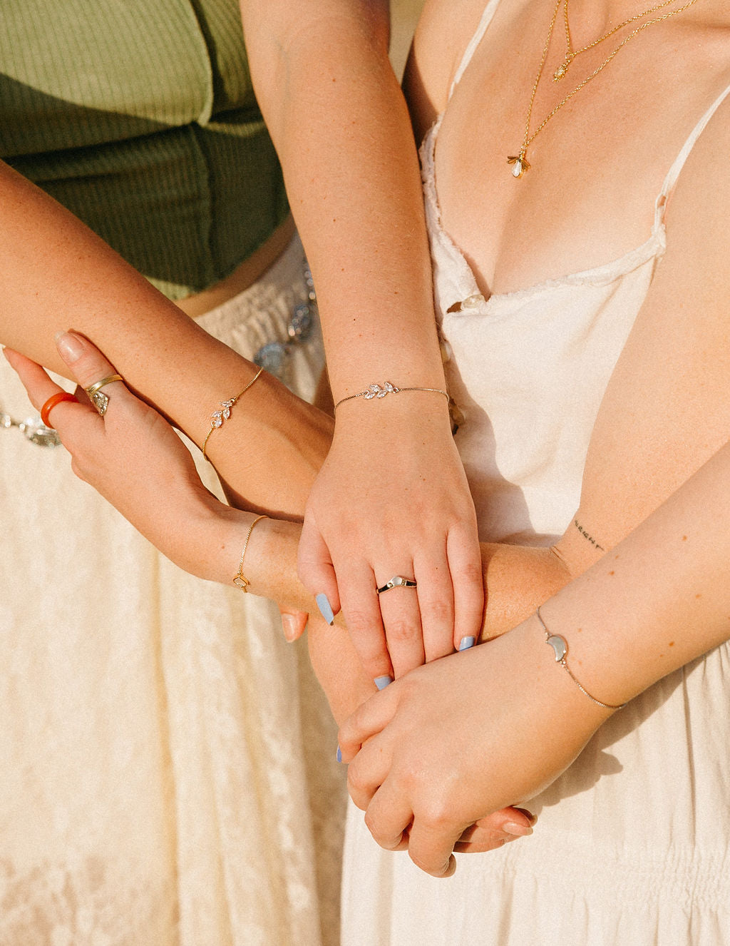 Matching dainty bracelets worn by two women, minimal gold and silver jewelry styling