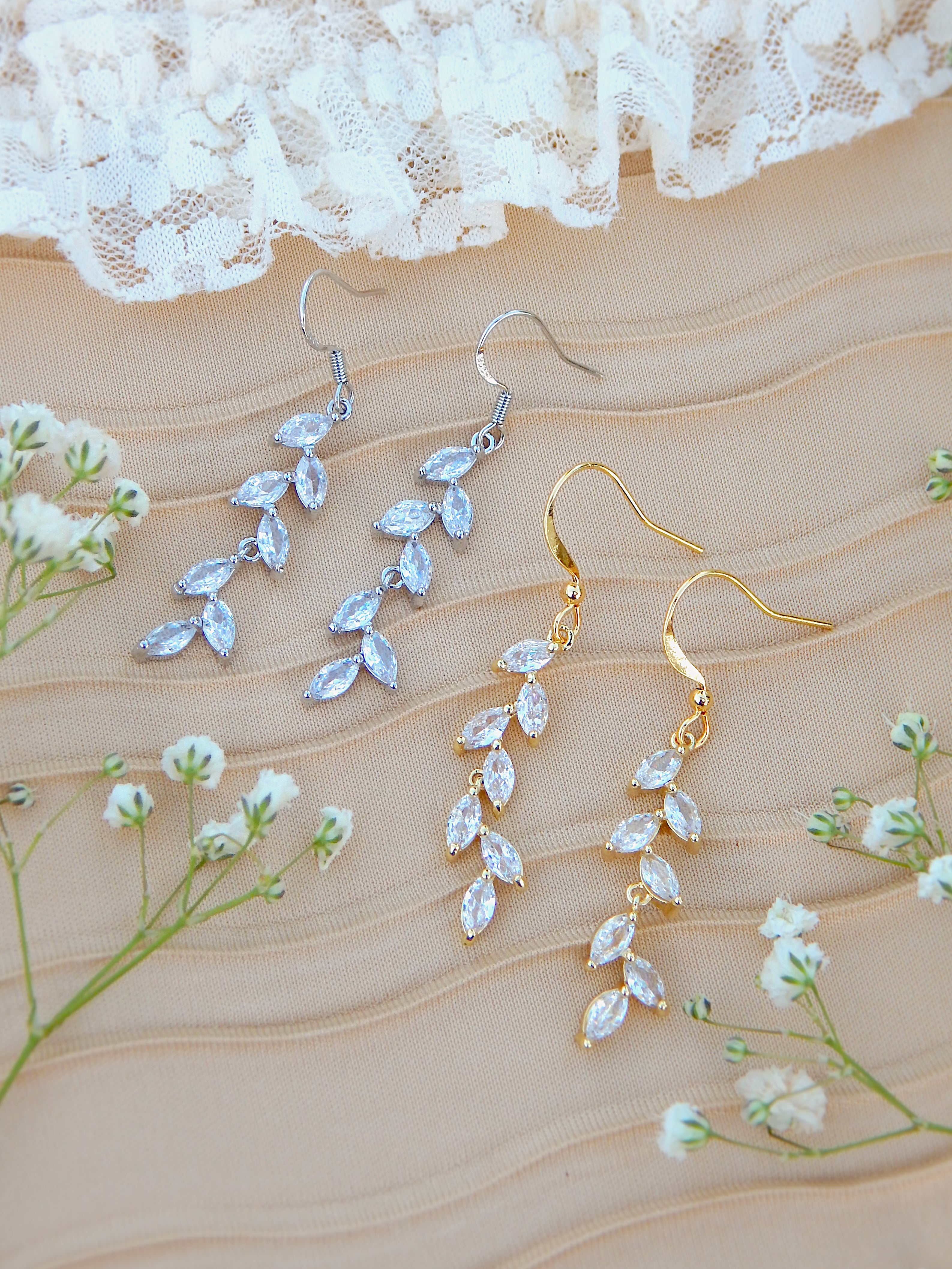 Gold and silver leaf dangle earrings on neutral background with floral accents, nature inspired jewelry