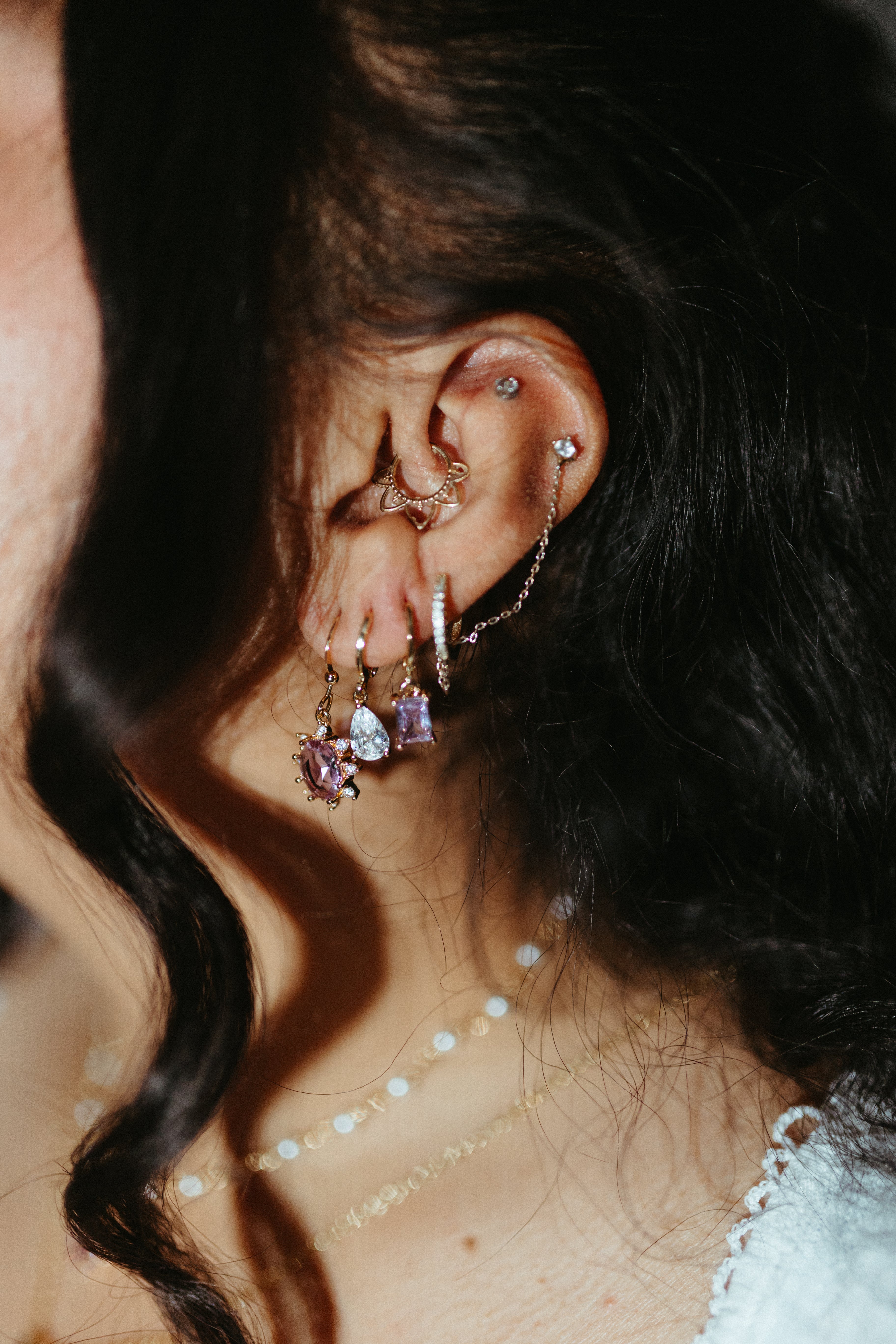 Gold teardrop huggie earrings worn in ear stack, layered jewelry styling with gemstone drops