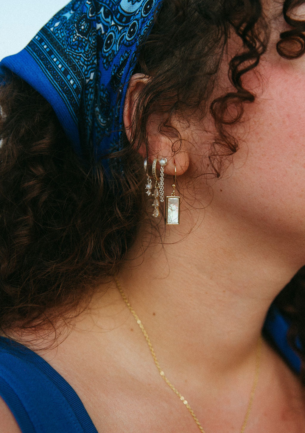 Woman wearing gold rectangle mother of pearl earrings, minimal dangle design shown in close-up side profile