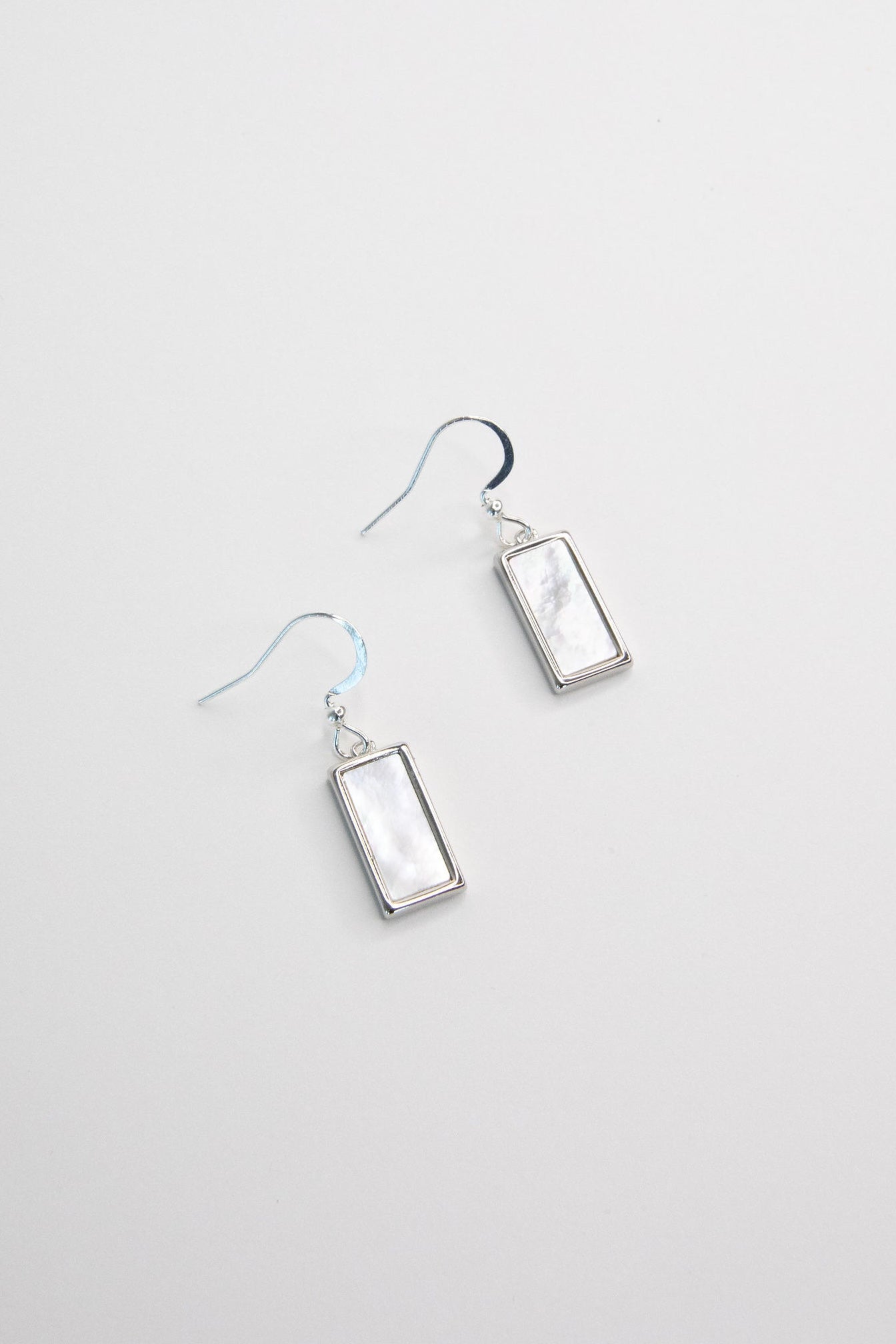 Silver rectangle mother of pearl earrings on white background, simple minimal dangle jewelry design
