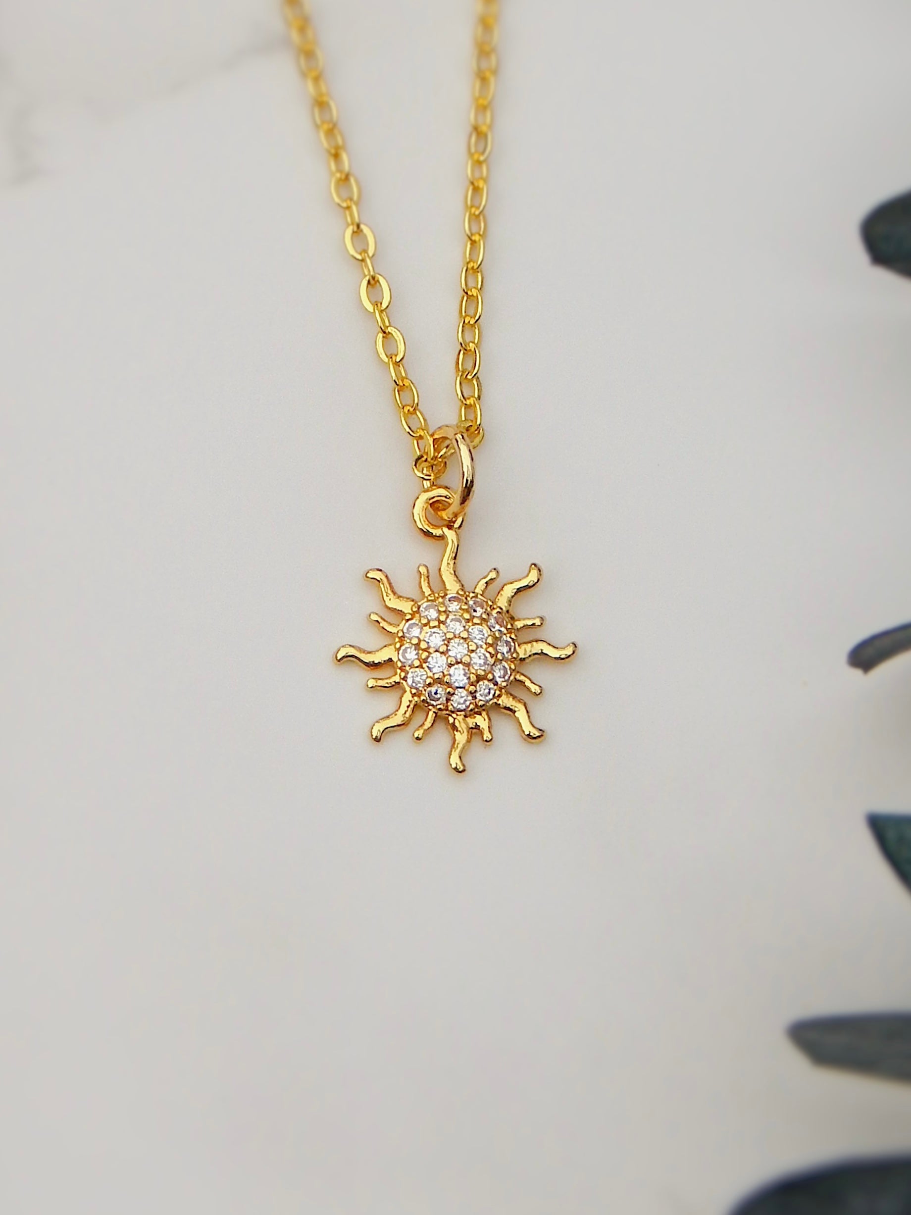 Full view of the Dawn Necklace featuring a gold sun pendant with cubic zirconia details on a gold chain.