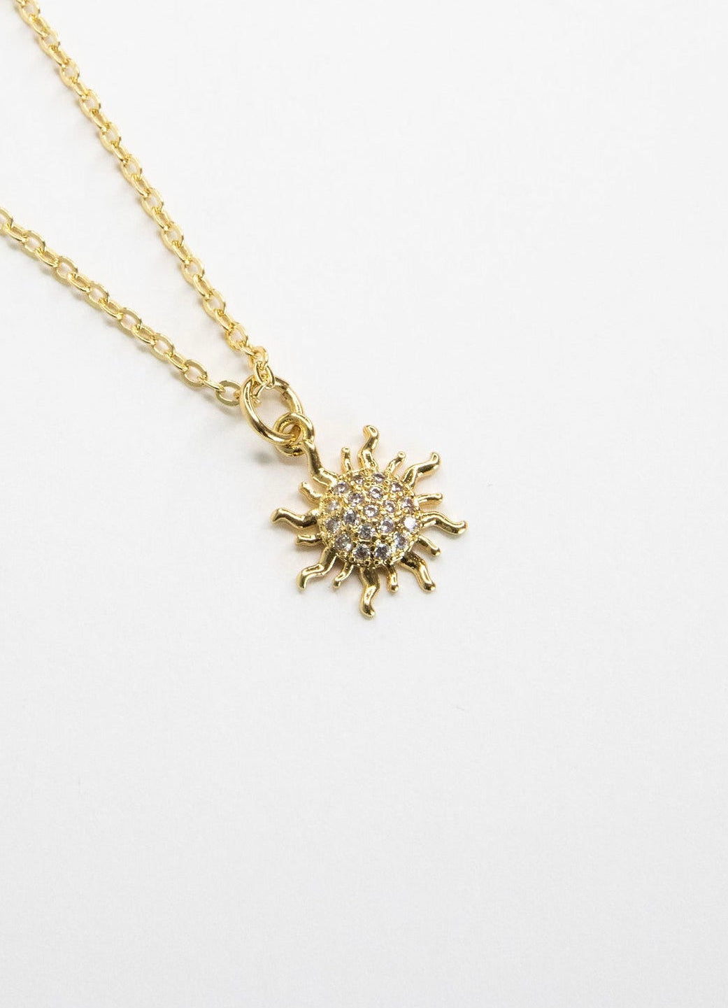 Close-up detail of the Dawn Necklace sun pendant showcasing sparkling cubic zirconia accents.