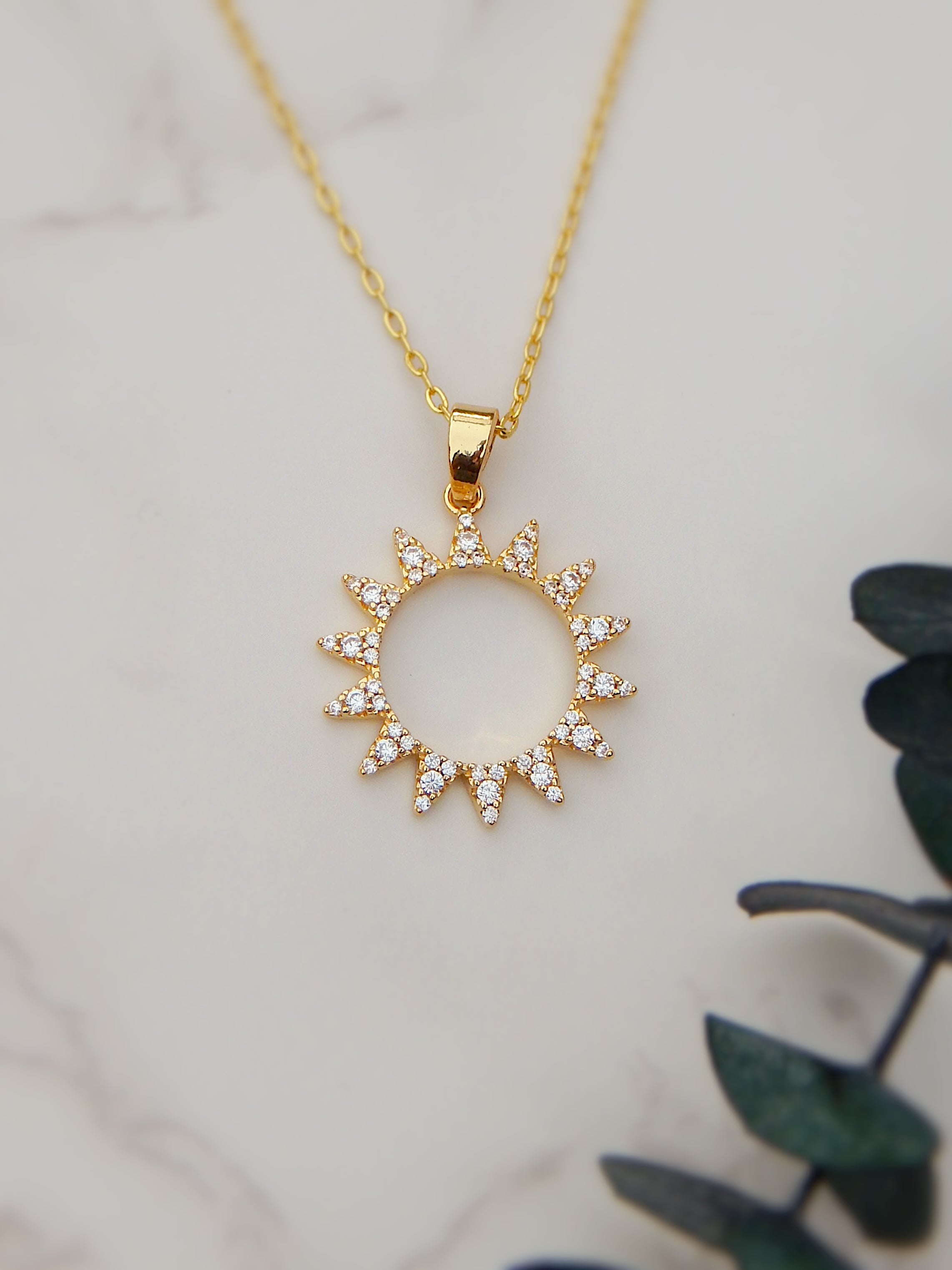 Gold sunburst necklace with cubic zirconia pendant on delicate chain