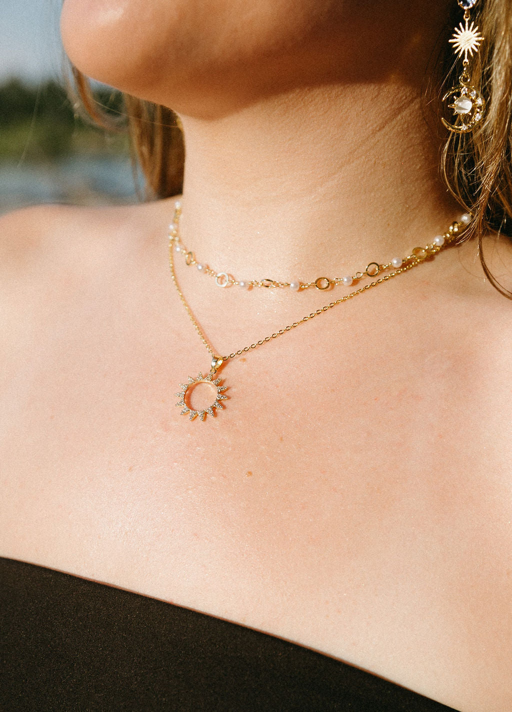 Gold sunburst necklace layered with beaded choker on model