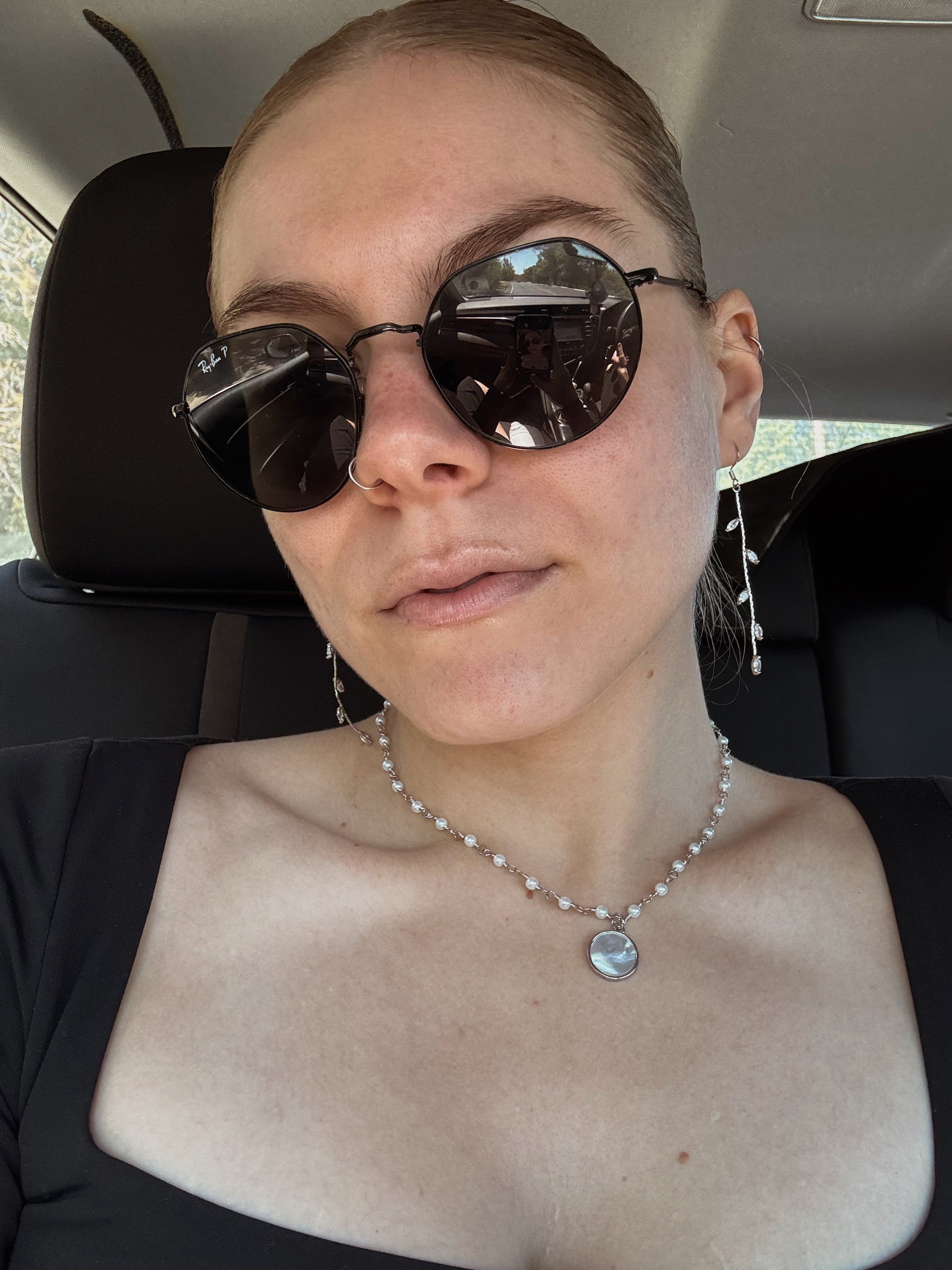 Close-up of woman wearing silver vine drop earrings with leaf details, styled with sunglasses and modern outfit