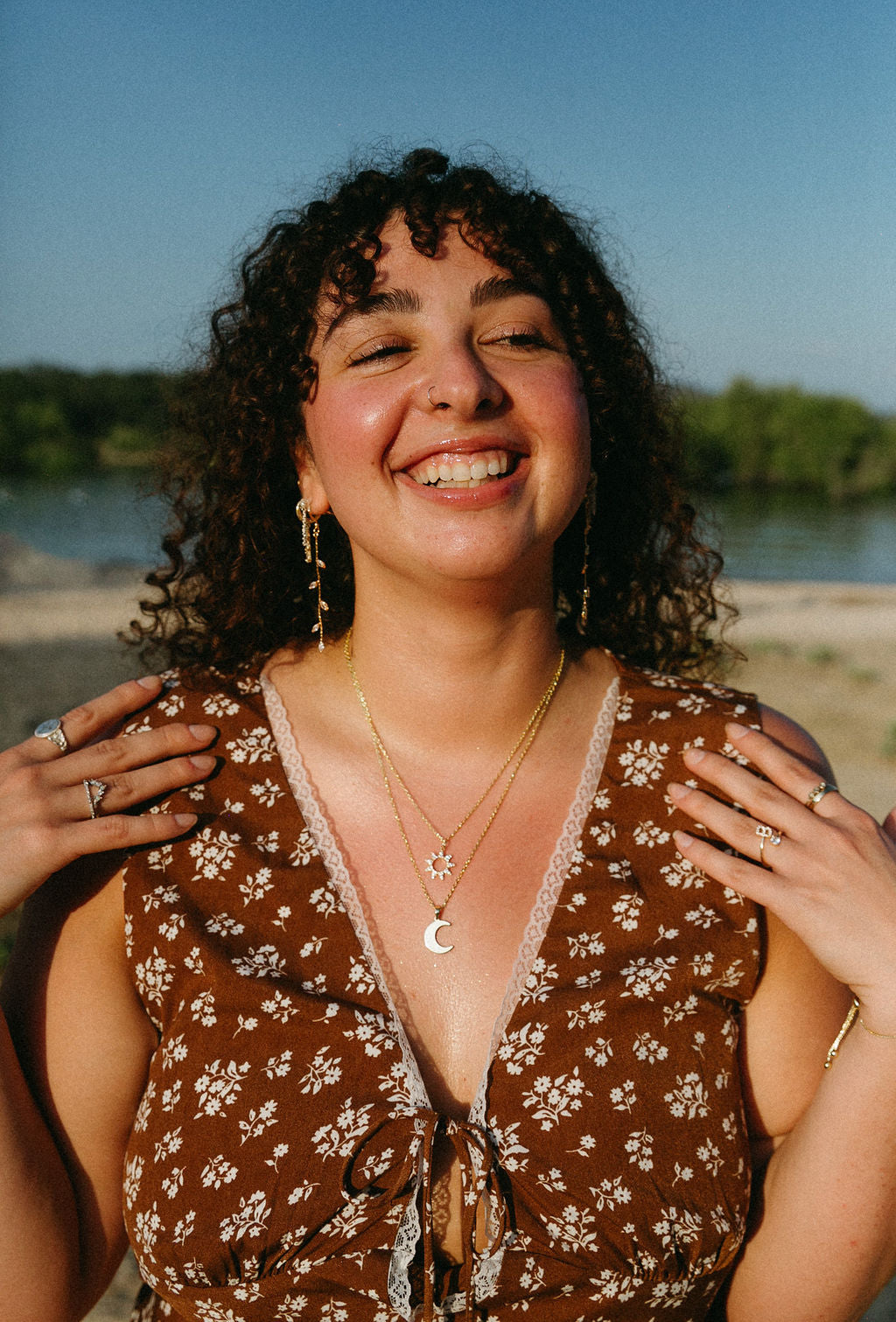 Woman smiling outdoors wearing long vine drop earrings, natural and feminine jewelry styling