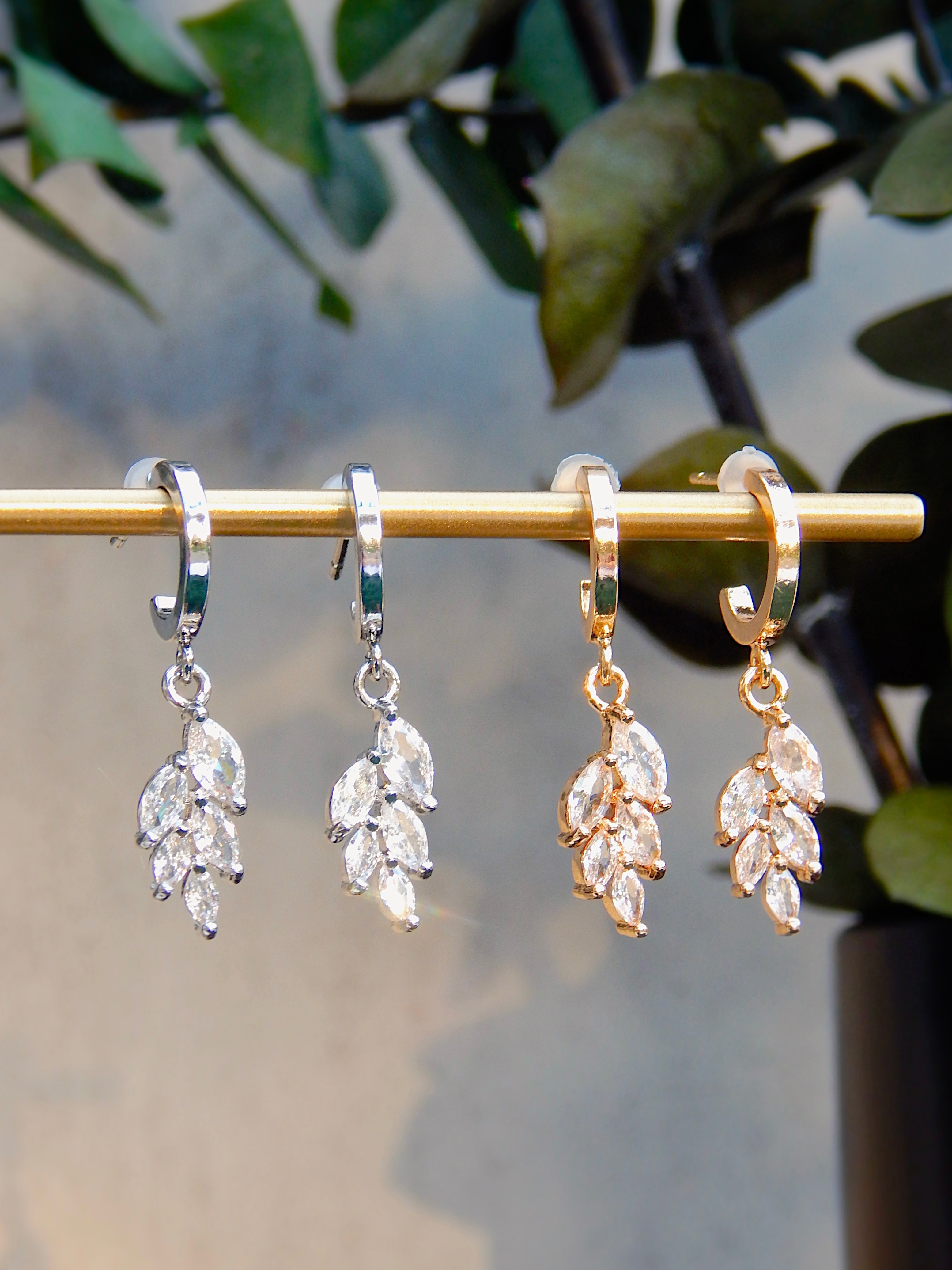 Gold and silver Ivy huggie earrings with cascading CZ leaf dangle shown side by side for color comparison