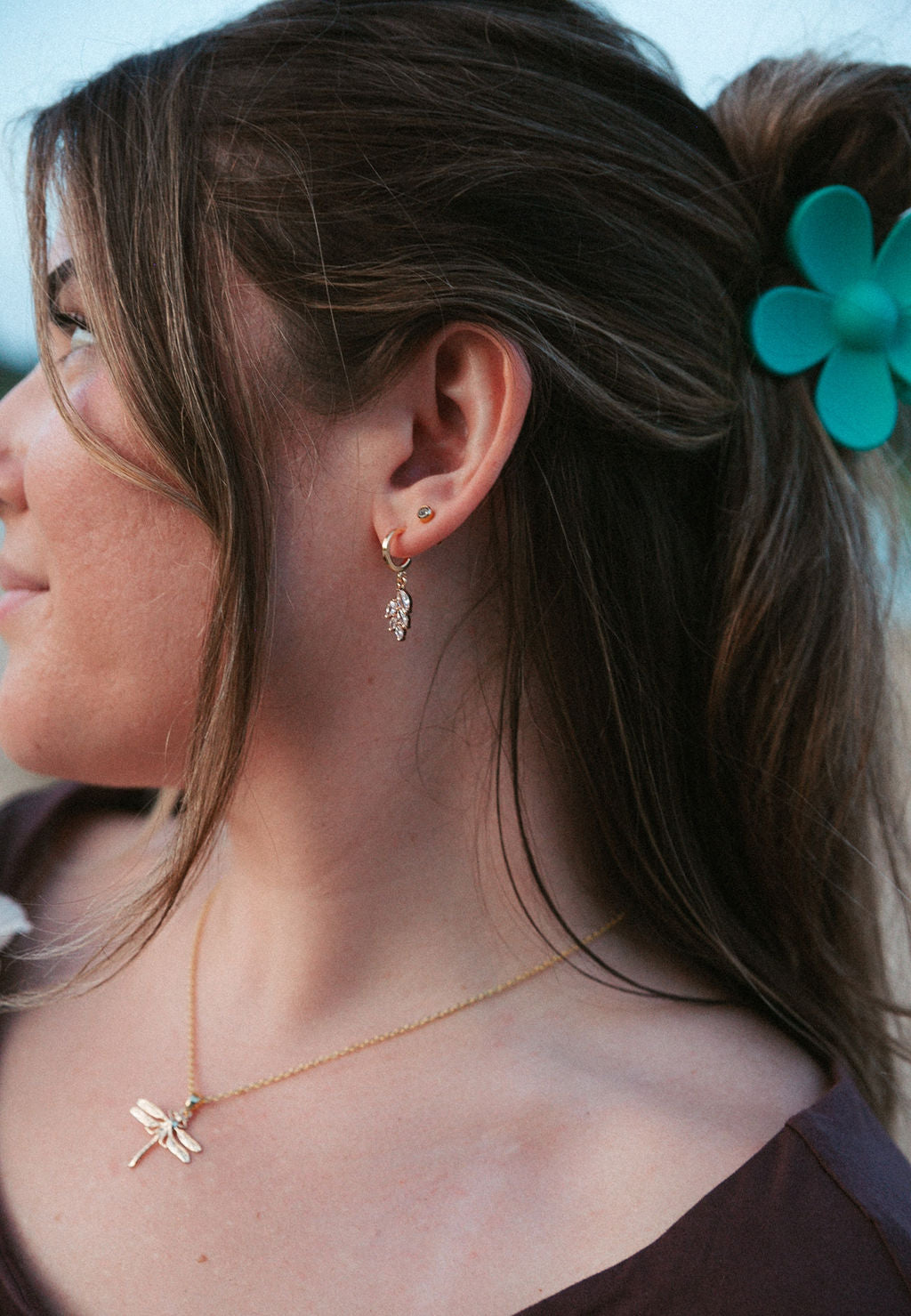 Woman wearing gold vine huggie earrings with leaf details, delicate everyday jewelry shown in close-up