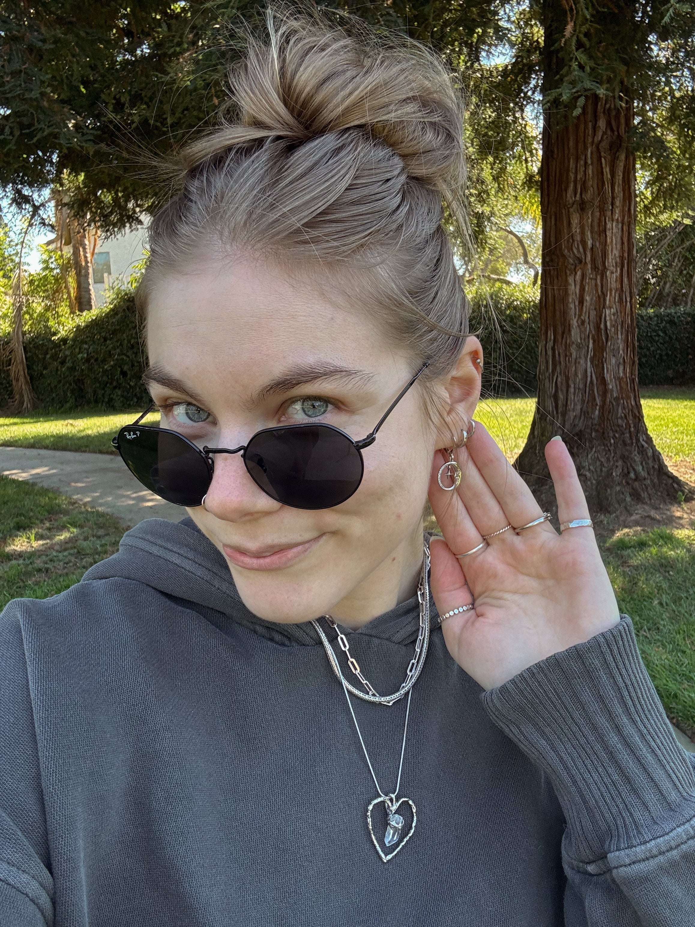 Woman wearing gold moon and star huggie earrings with layered necklaces outdoors