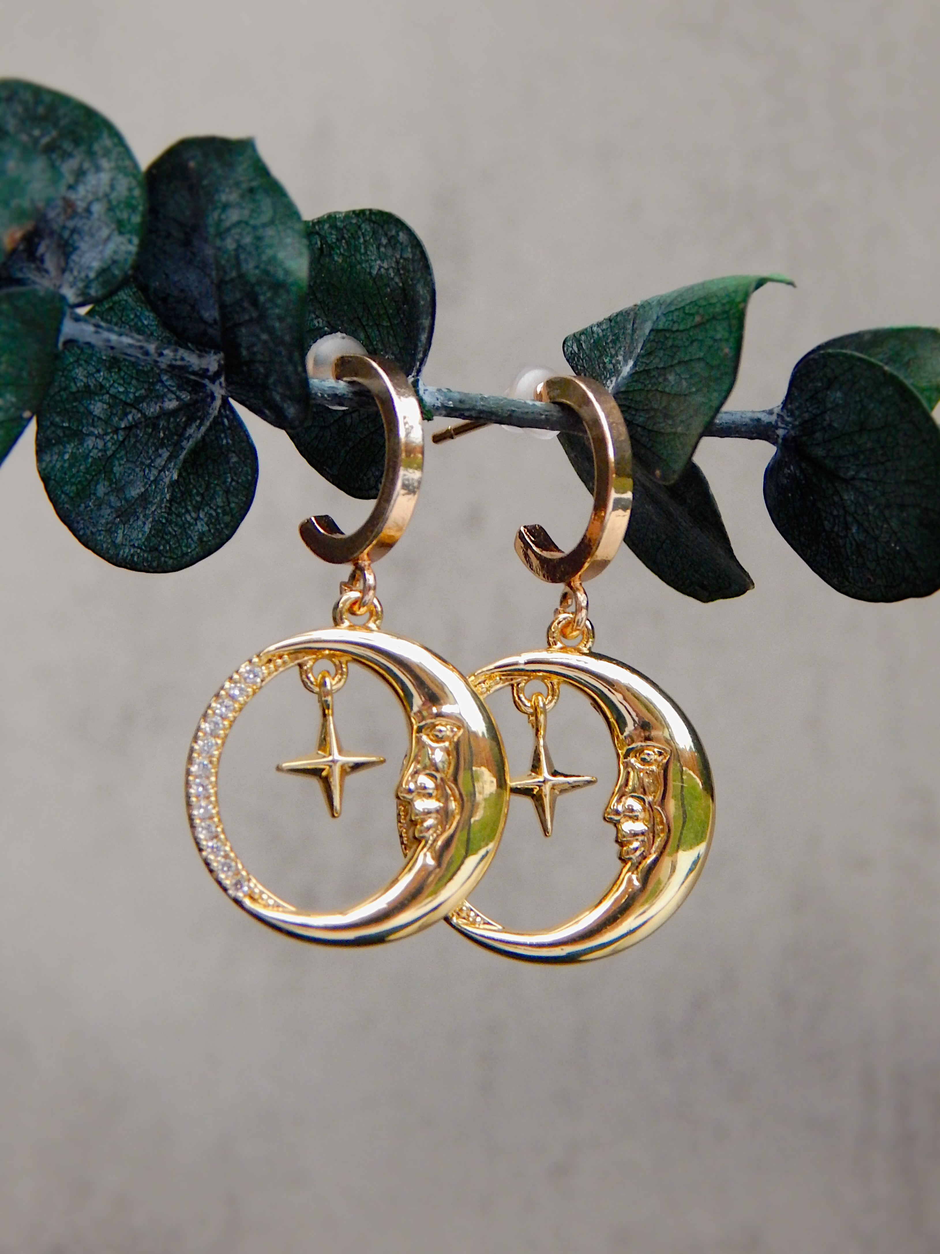 Gold moon and star huggie earrings with circular pendant on natural branch