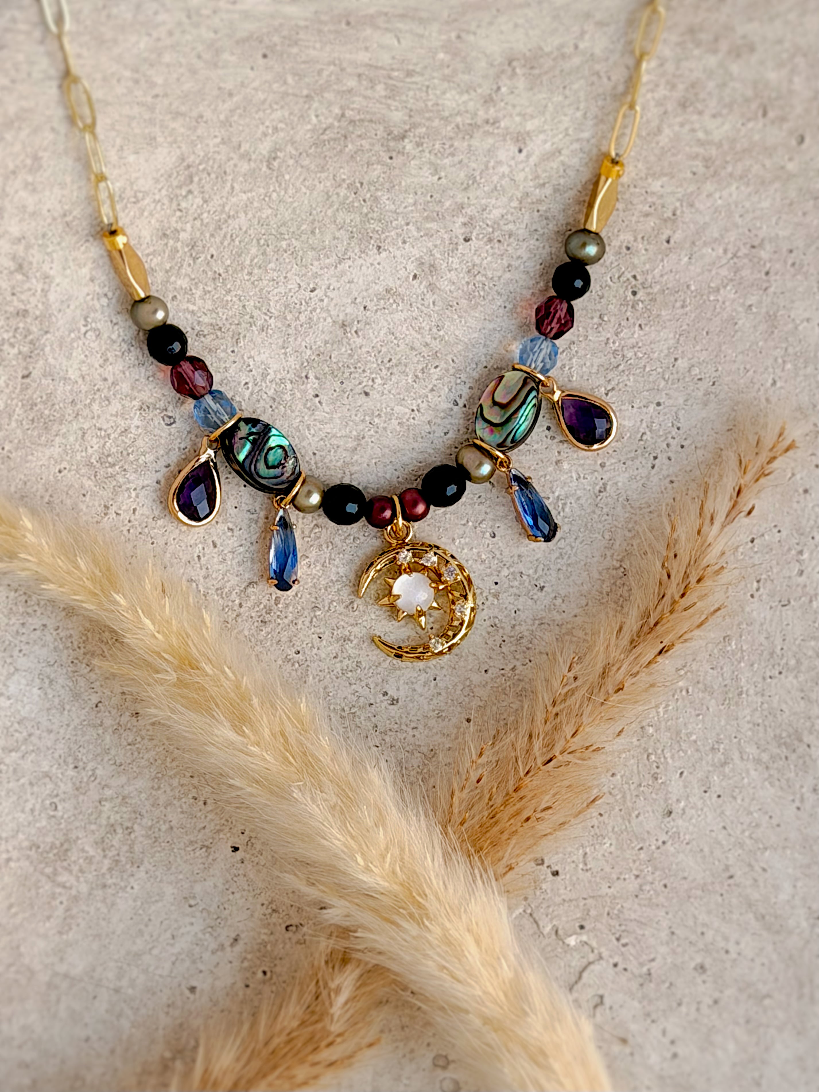 Handmade one-of-a-kind Crescent Moon beaded charm necklace featuring genuine abalone shell, natural gemstones, celestial charms, and an 18-inch gold paperclip chain by Rising Soul Jewelry.