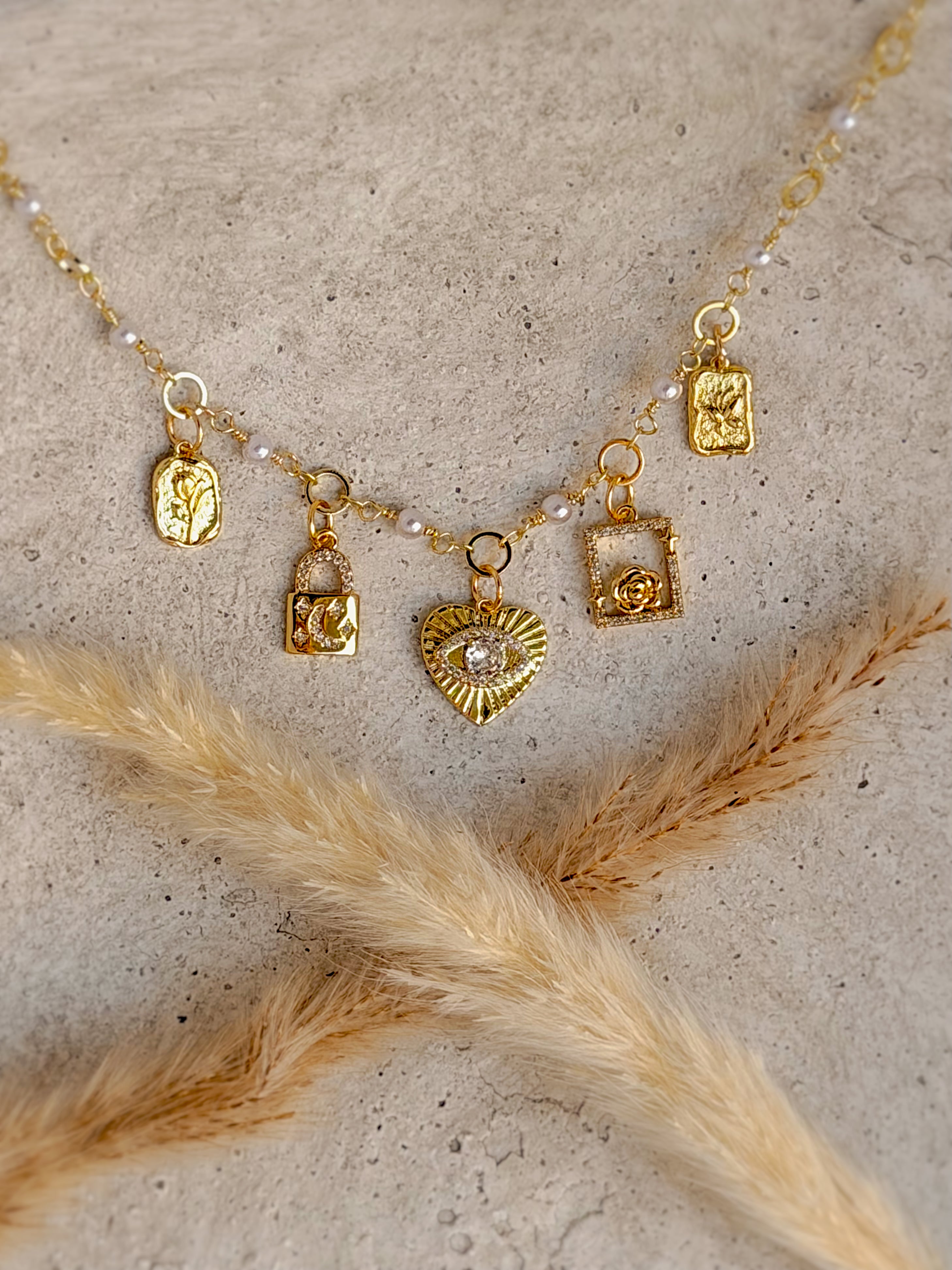 One of a Kind Heart Charm Necklace with authentic freshwater pearls, cubic zirconia heart, moon lock, rose, and botanical gold charms handcrafted by Rising Soul Jewelry.
