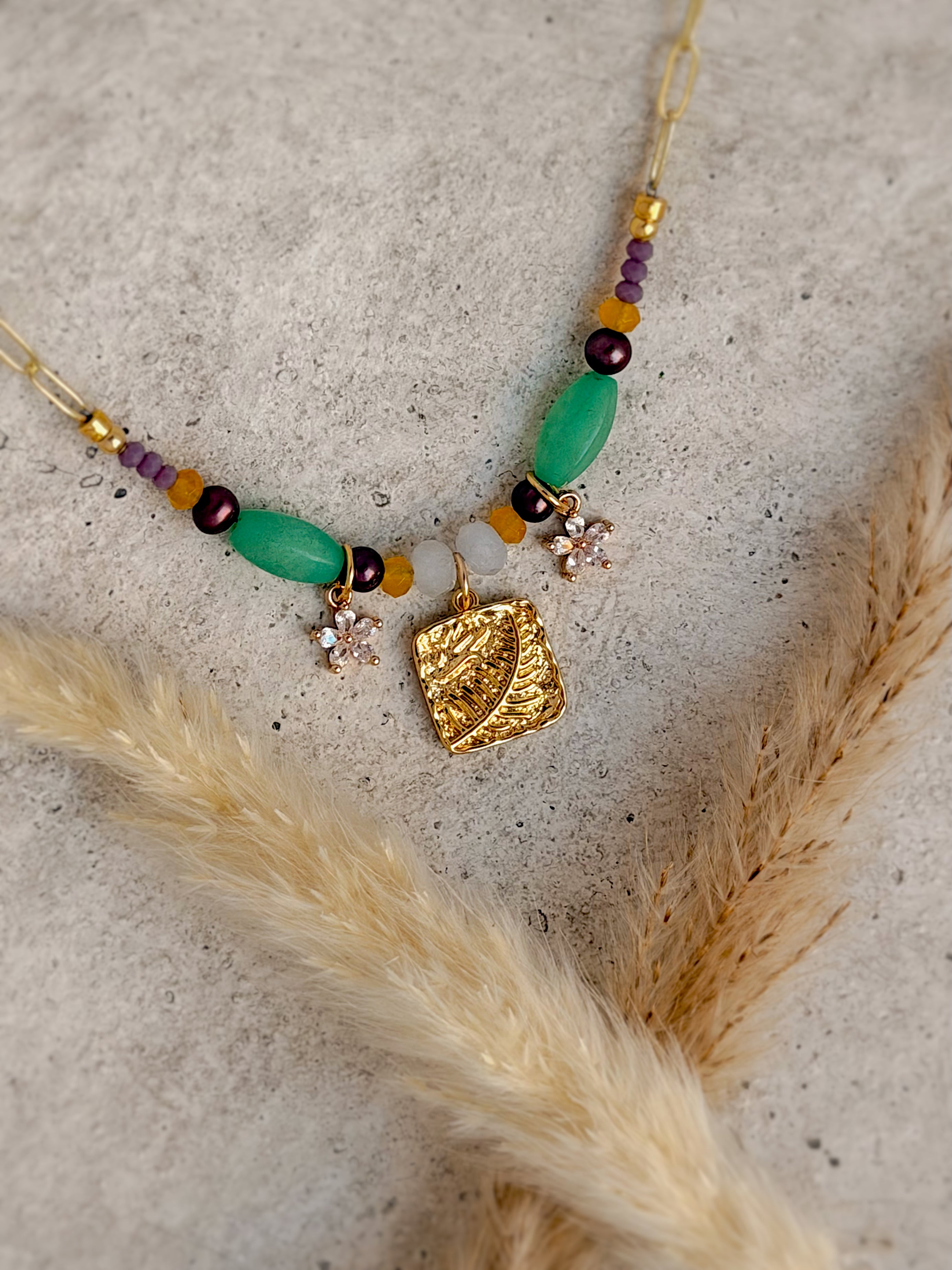 Handmade one-of-a-kind leaf beaded charm necklace featuring natural green, plum, honey, and white gemstones with a gold botanical leaf charm and floral accents on an 18-inch paperclip chain.