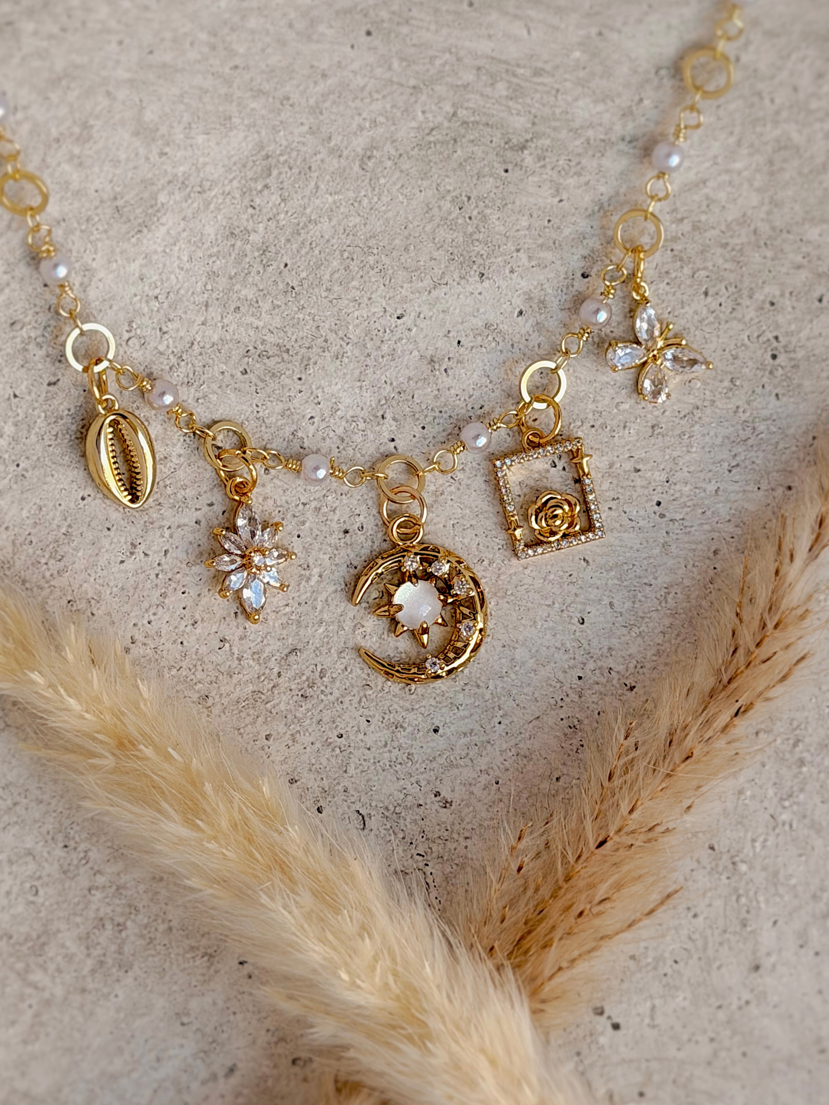 One of a Kind Moon and Star Charm Necklace with authentic freshwater pearls, genuine mother of pearl, cubic zirconia butterfly, rose, shell, and celestial gold charms handcrafted by Rising Soul Jewelry.