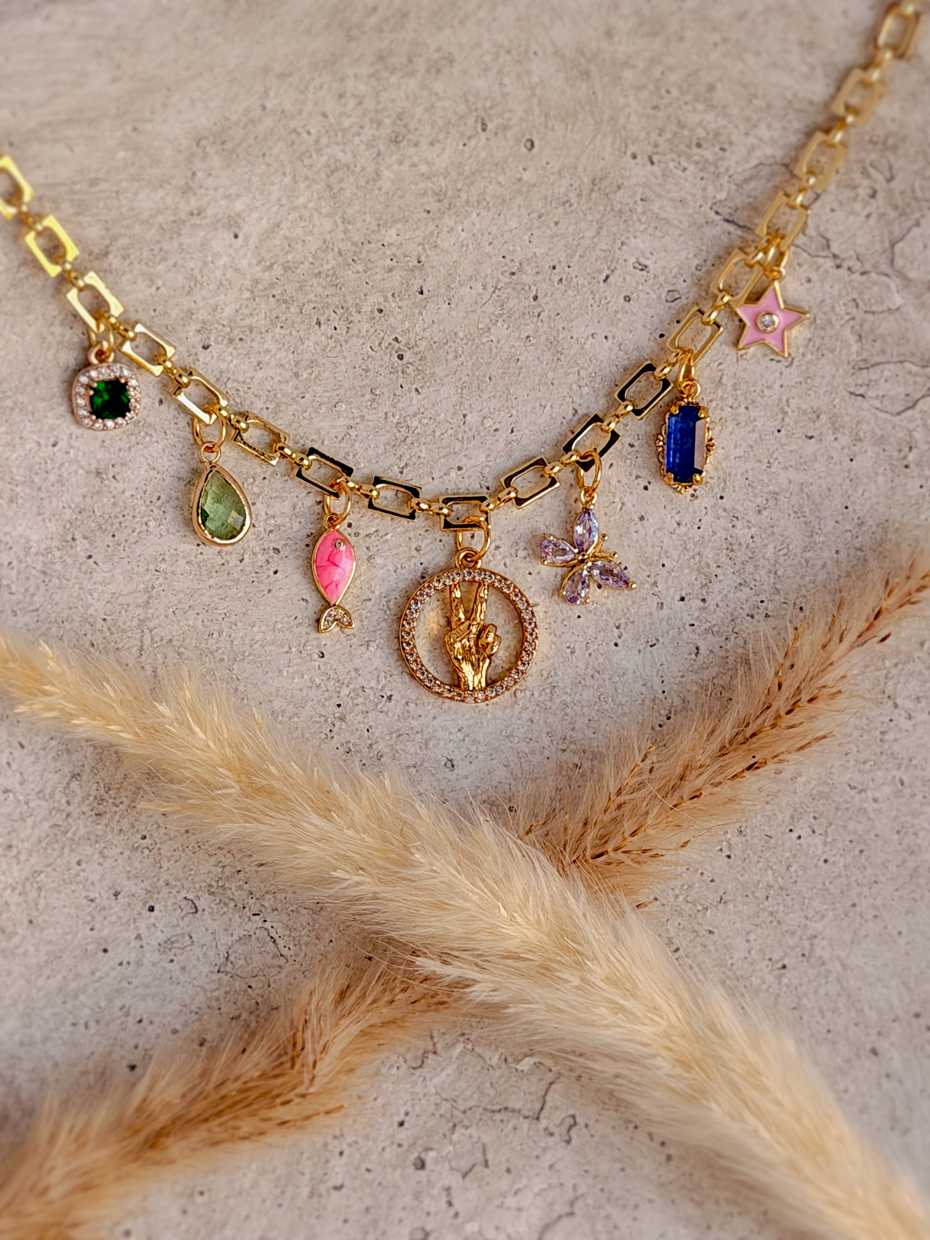 One of a Kind Peace Charm Necklace with colorful enamel fish and star charms, cubic zirconia butterfly, vibrant gemstone accents, and gold paperclip chain handcrafted by Rising Soul Jewelry.