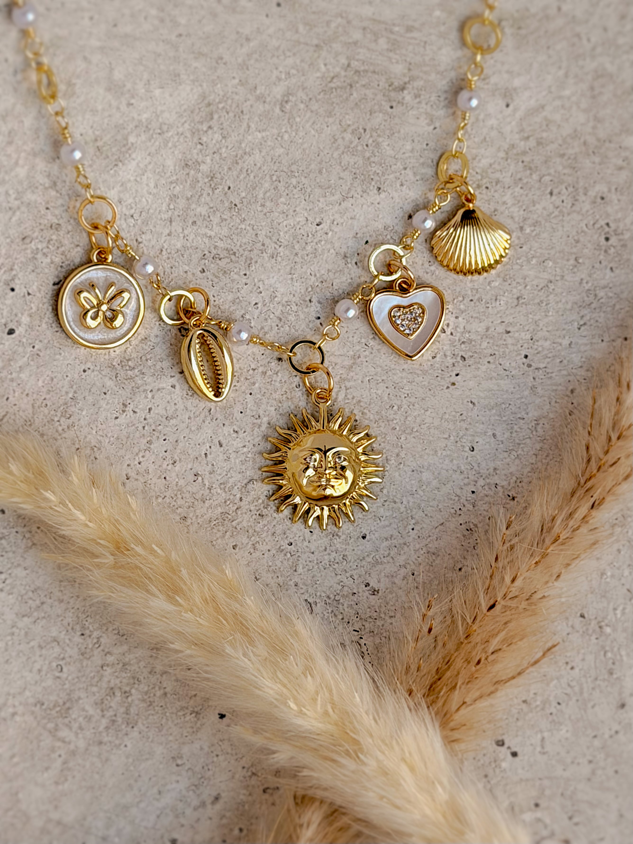One of a Kind Sun Charm Necklace with authentic freshwater pearls, genuine mother of pearl charms, cubic zirconia details, shell, butterfly, heart, and gold sun handcrafted by Rising Soul Jewelry.