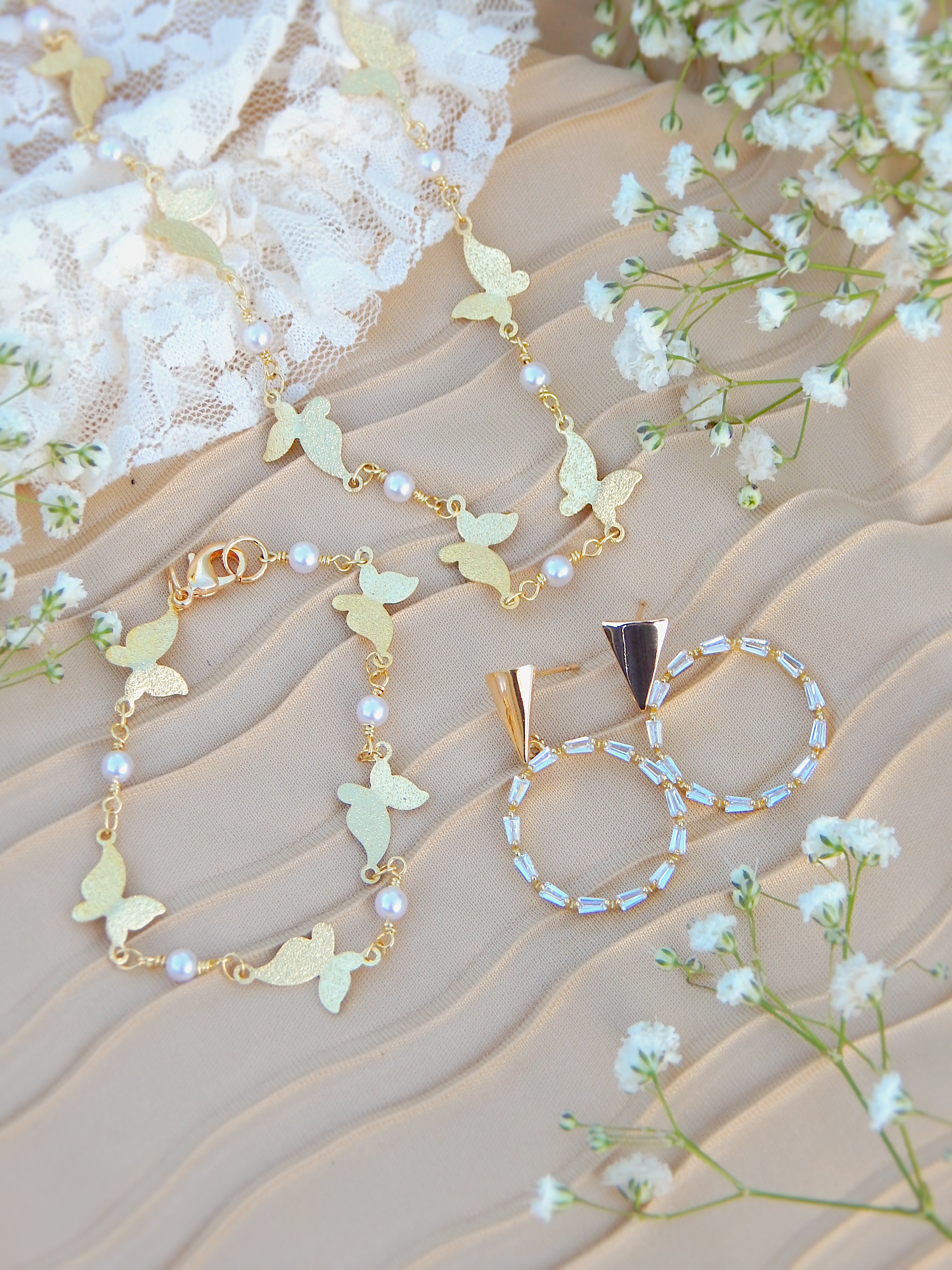 Gold circle drop earrings with cubic zirconia styled with layered gold necklace on soft neutral background with flowers