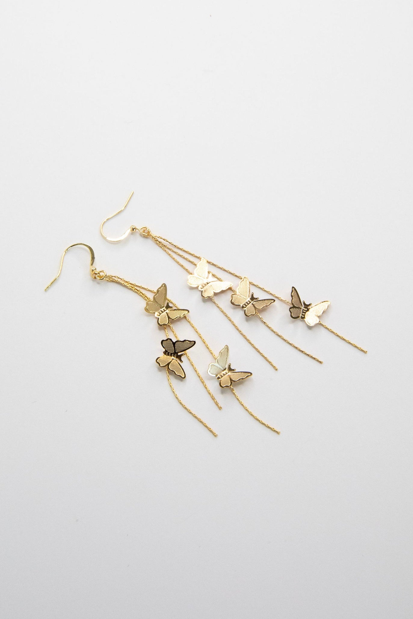 Gold butterfly drop earrings with cascading chains on white background