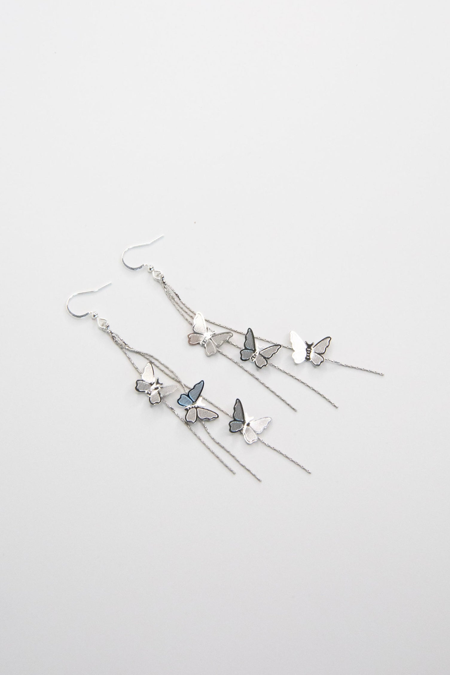 Silver butterfly drop earrings with cascading chains on white background