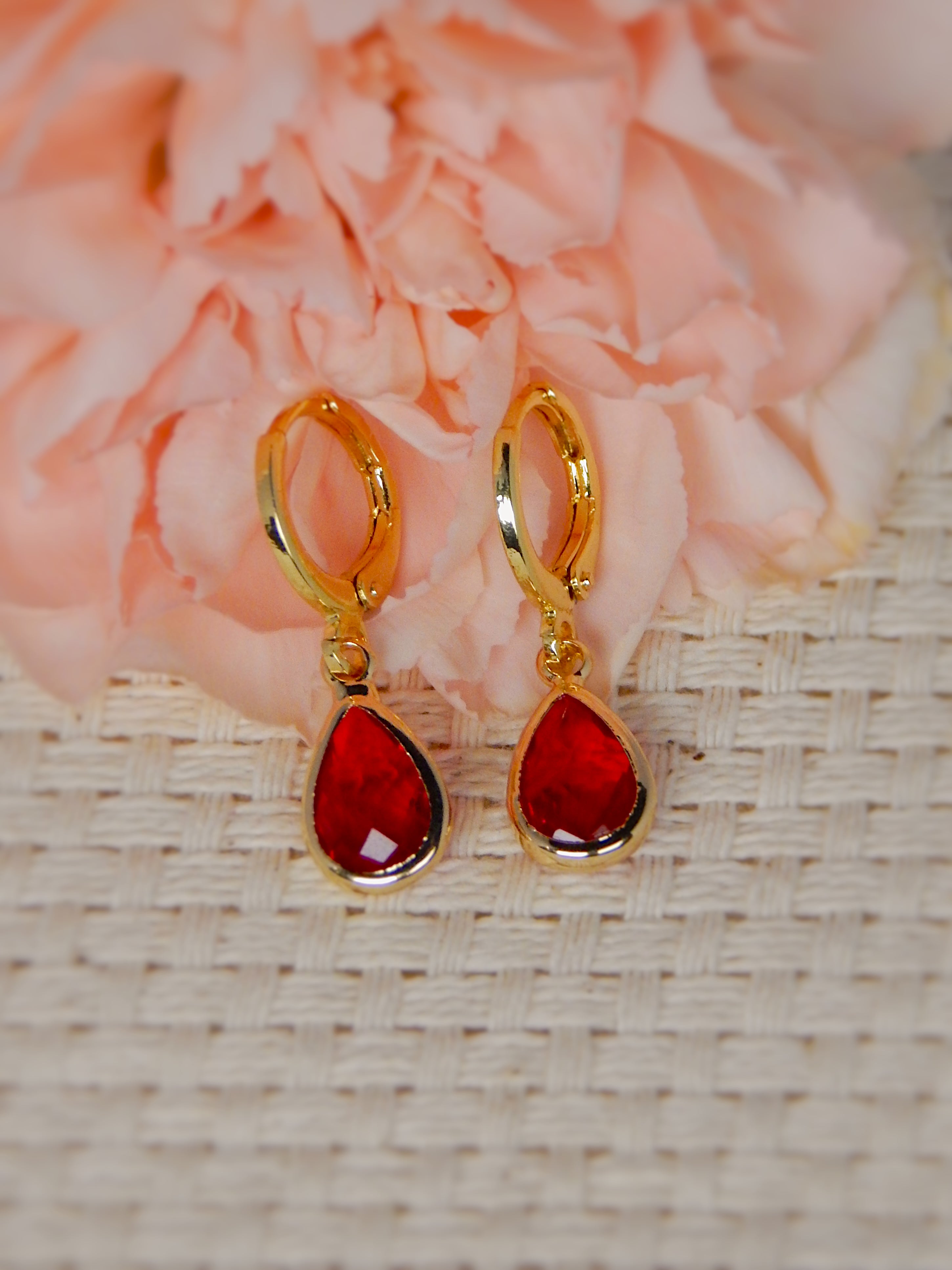 Gold huggie earrings with red teardrop gemstone drop, vibrant feminine jewelry