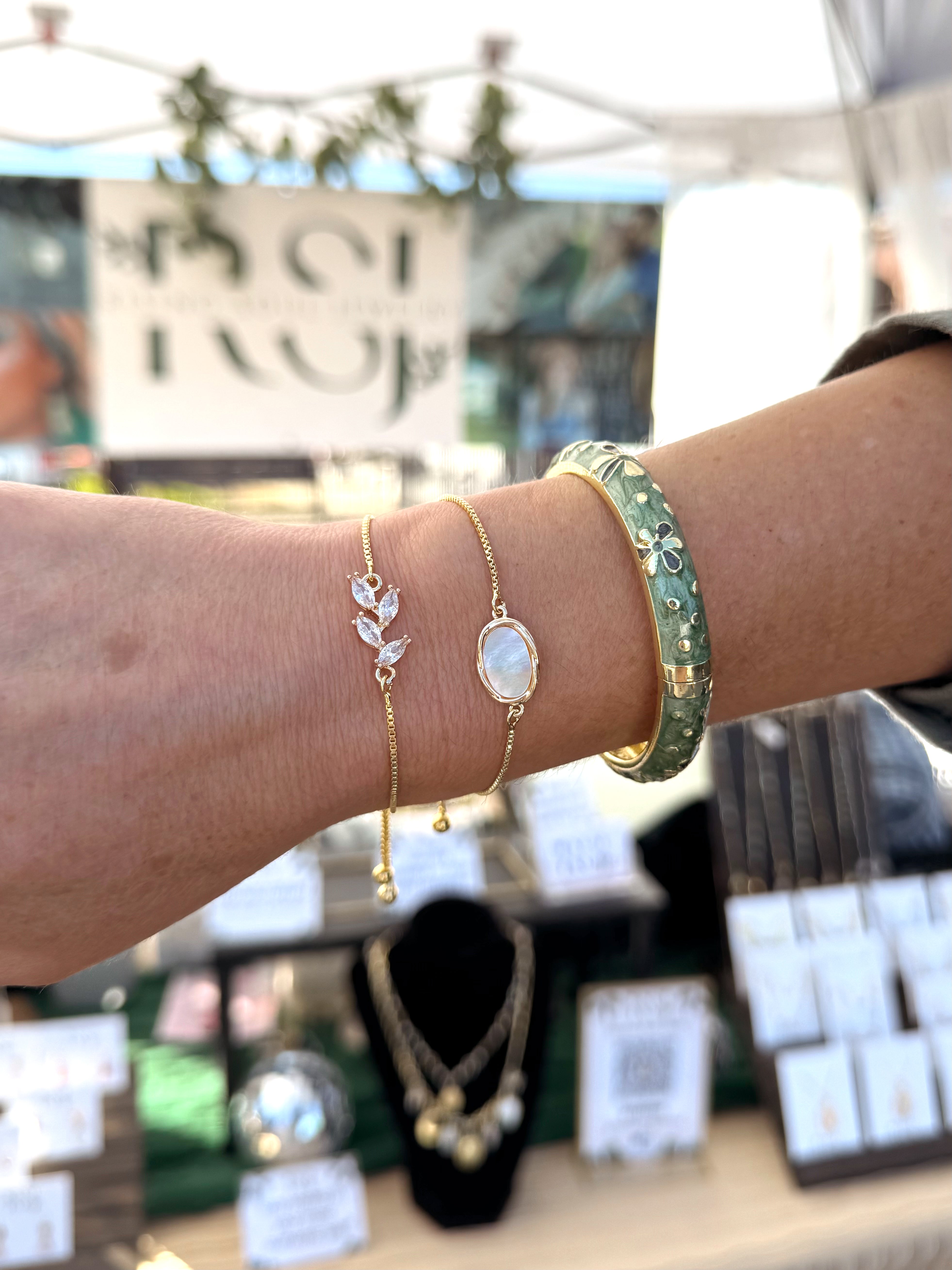 Gold floral chain bracelet worn on wrist, dainty adjustable jewelry styled at outdoor market