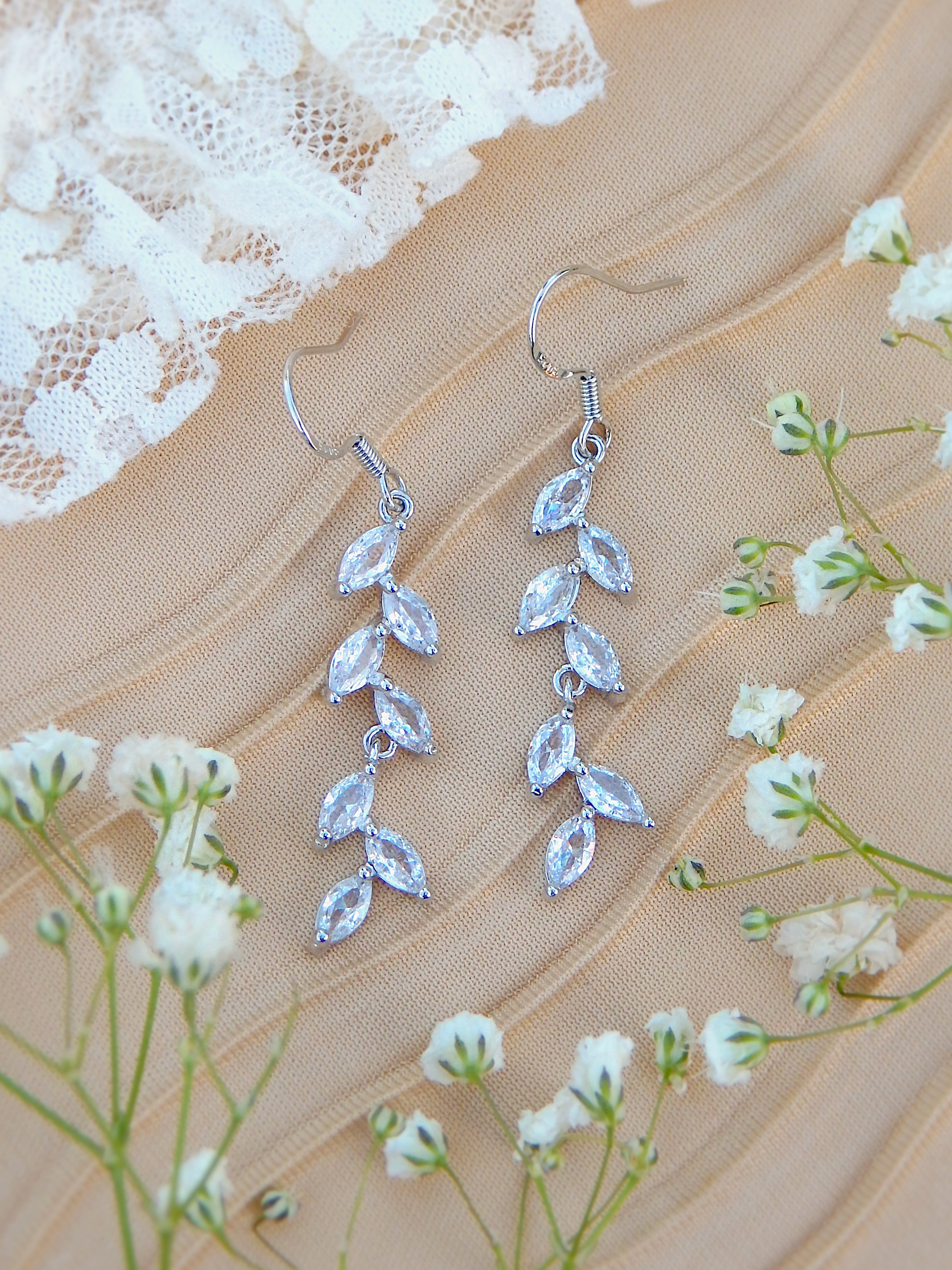 Silver cubic zirconia vine earrings with leaf design on neutral background