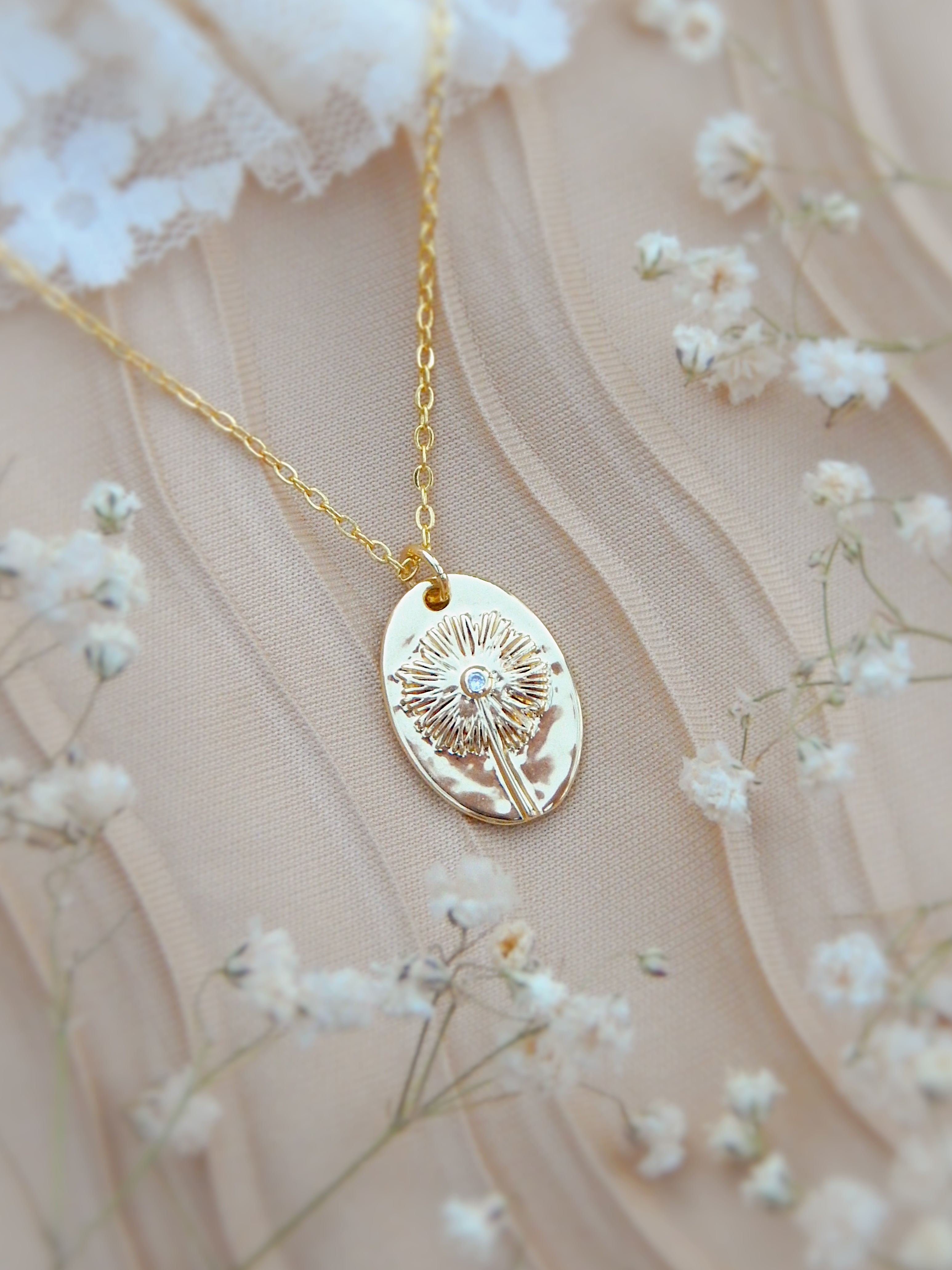 Close-up of gold dandelion wish necklace pendant with engraved radiating dandelion design