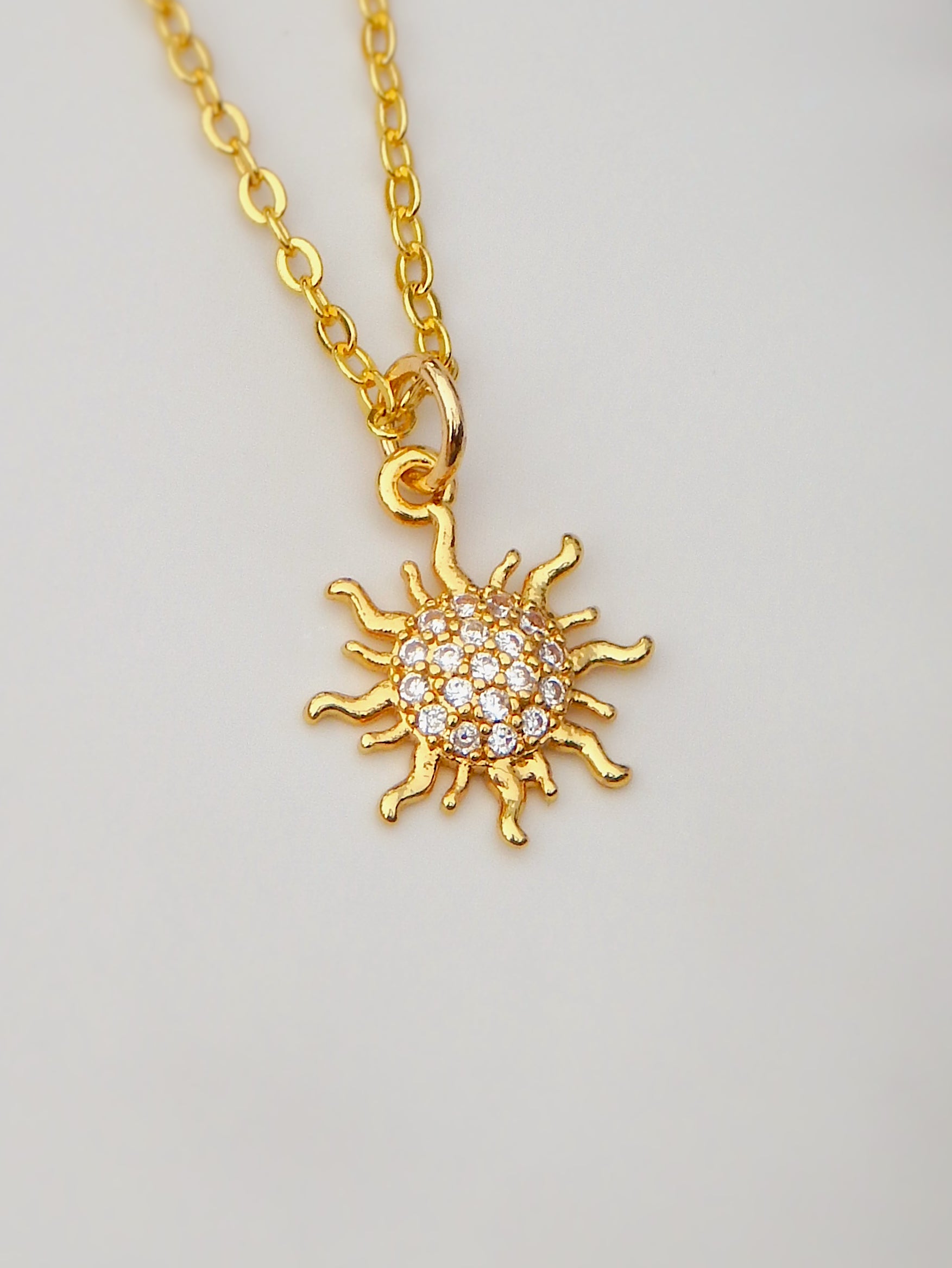 Dawn Necklace featuring a gold sun pendant with sparkling cubic zirconia details on a delicate gold chain.