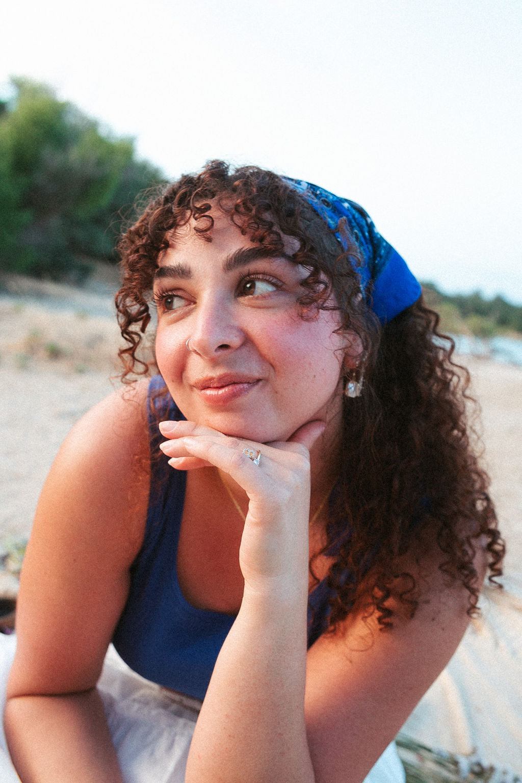 Woman wearing gold mother of pearl earrings in natural outdoor setting, soft and feminine jewelry look