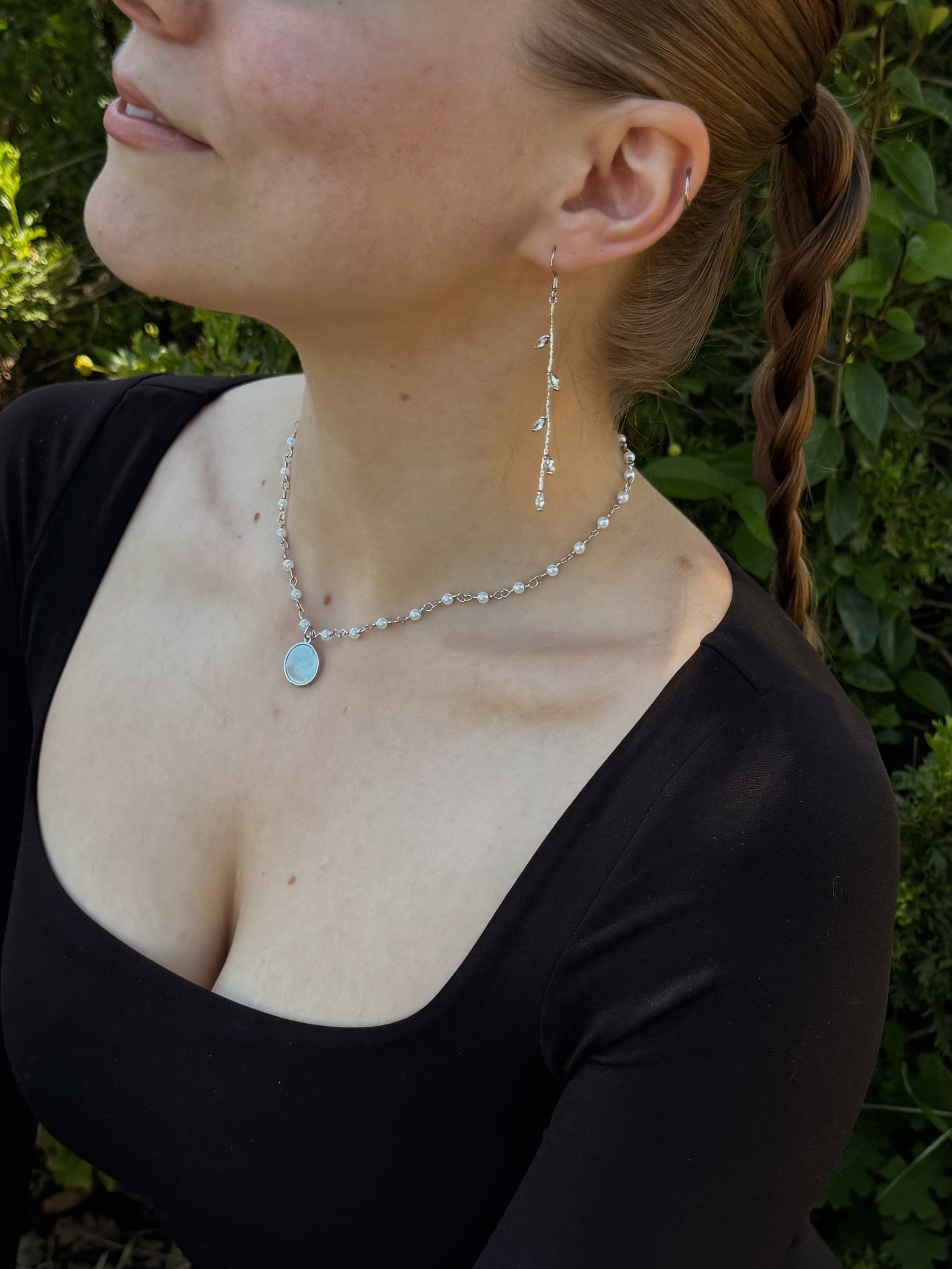 Woman wearing long silver vine drop earrings with leaf details, elegant dangle earrings shown in close-up
