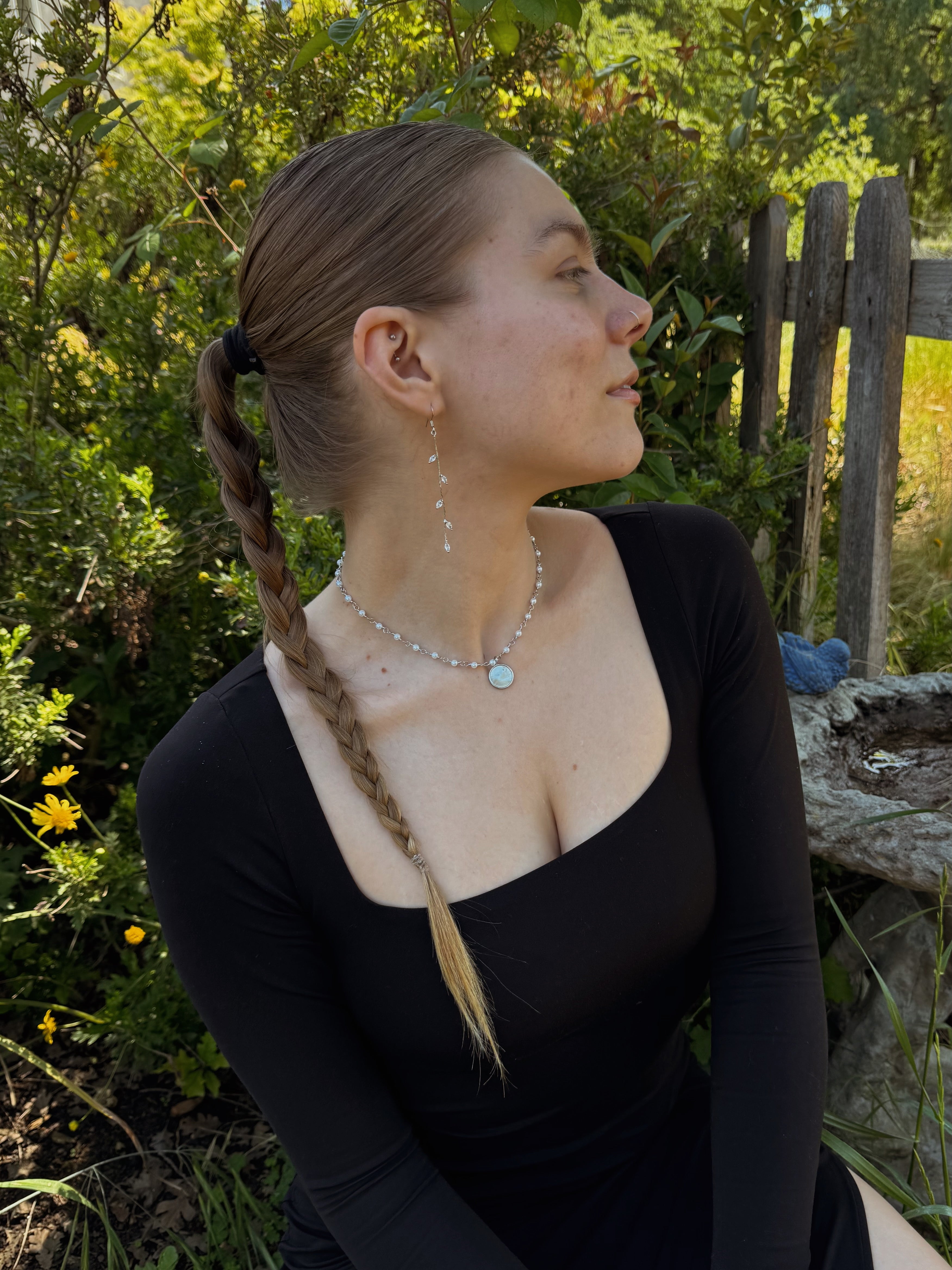 Side profile of woman wearing long vine drop earrings with leaf details, elegant elongated silhouette