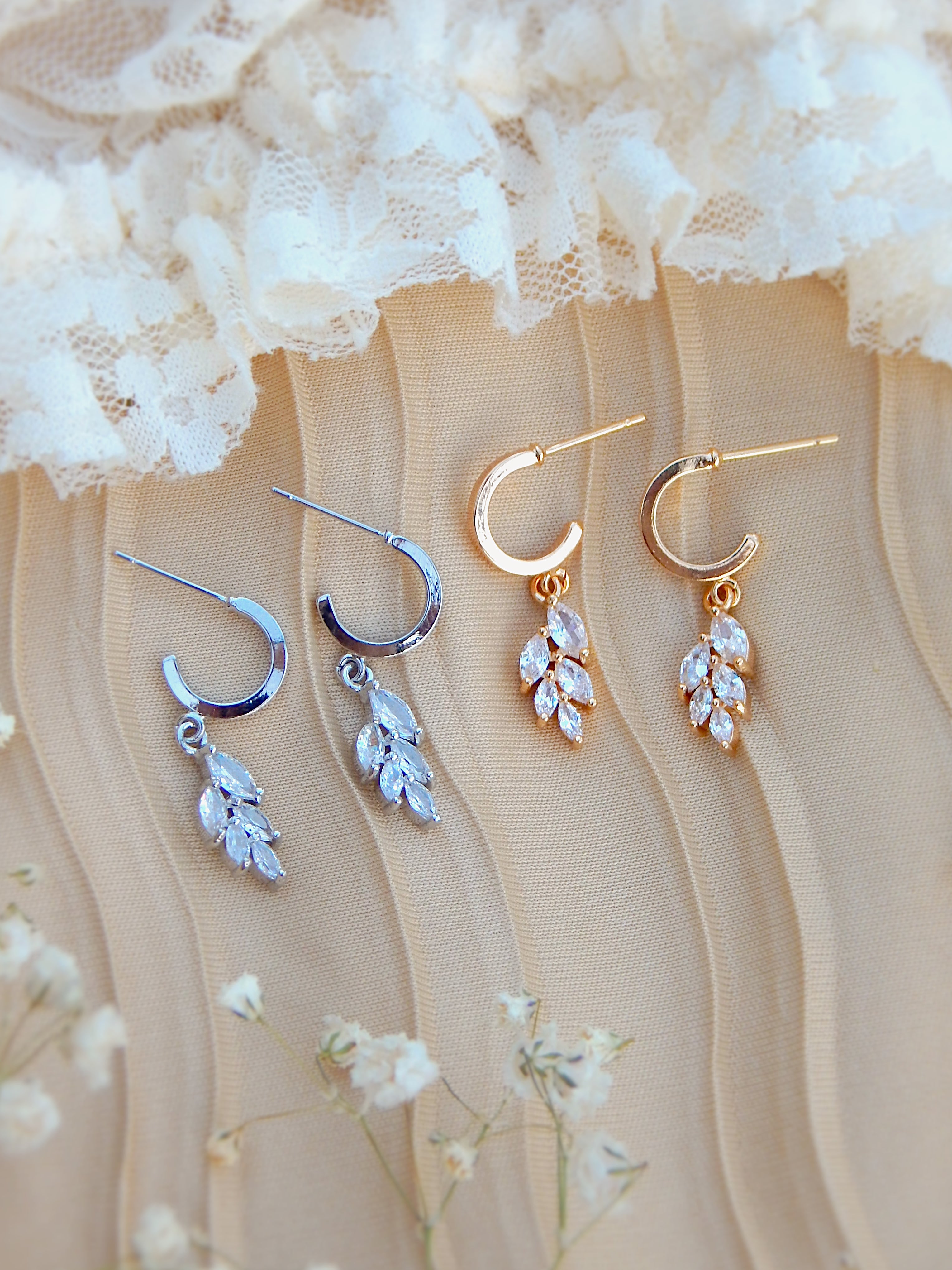 Gold and silver vine huggie earrings displayed together, showing both color options with leaf drop design