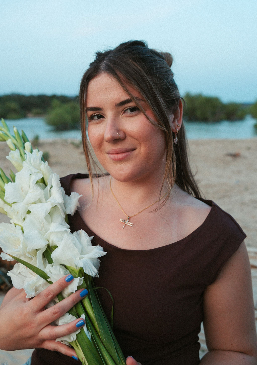 Woman wearing vine huggie earrings outdoors, soft feminine jewelry styling with natural light