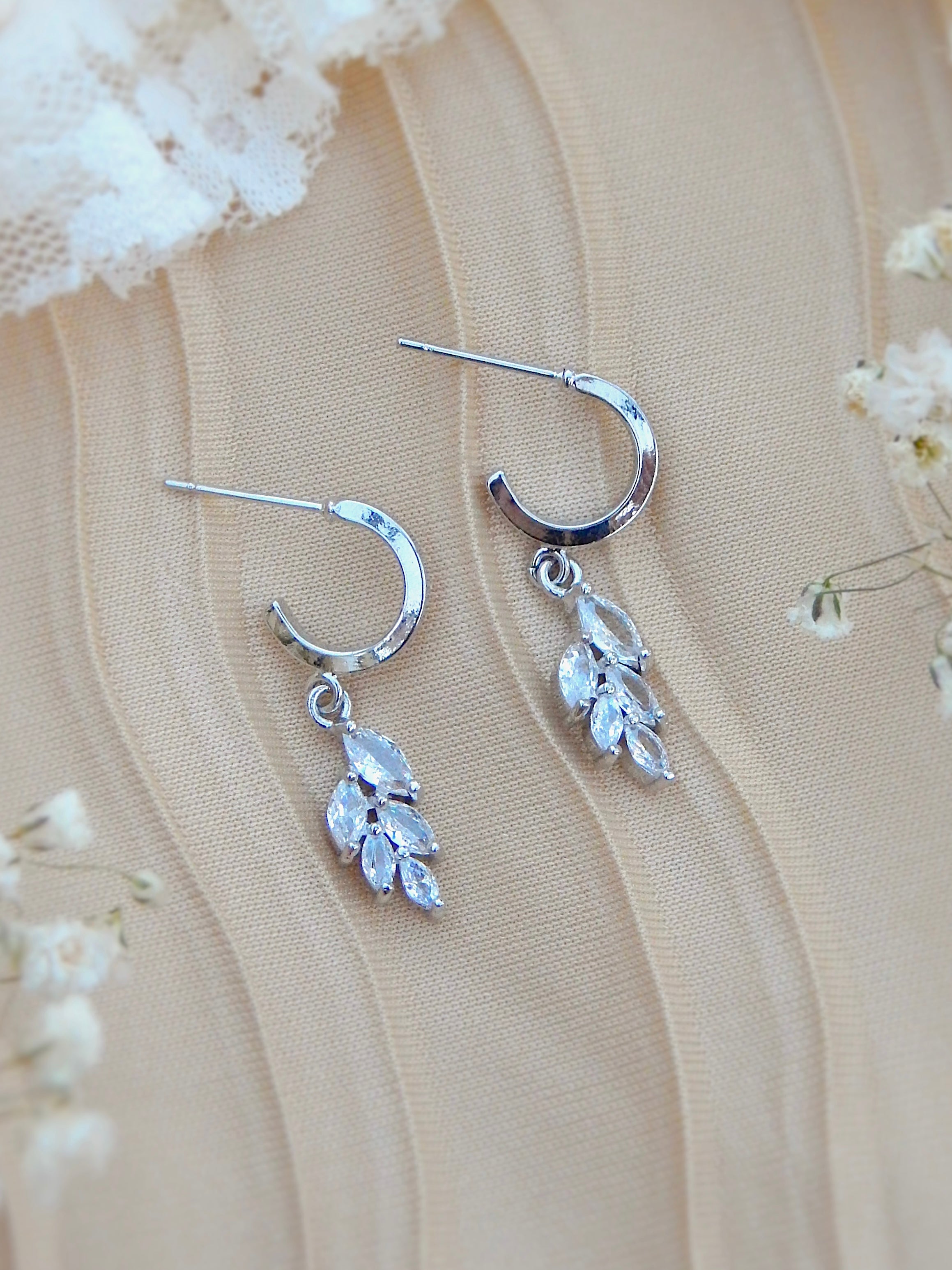 Silver huggie earrings with vine leaf cubic zirconia design on neutral background, minimal everyday jewelry