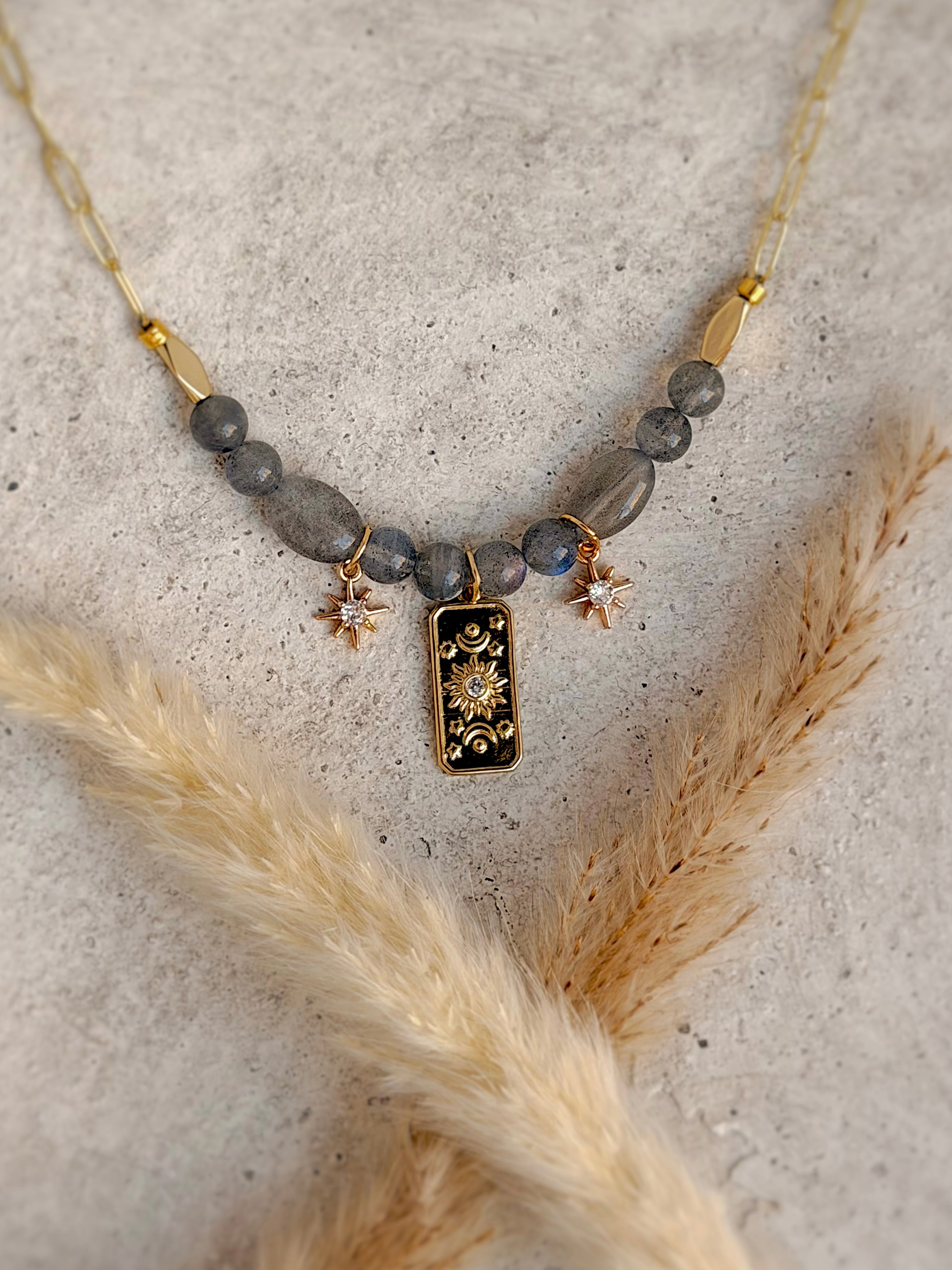 Handmade one-of-a-kind Celestial Sun beaded charm necklace featuring natural labradorite gemstones, black enamel celestial sun pendant, star charms, and an 18-inch gold paperclip chain by Rising Soul Jewelry.