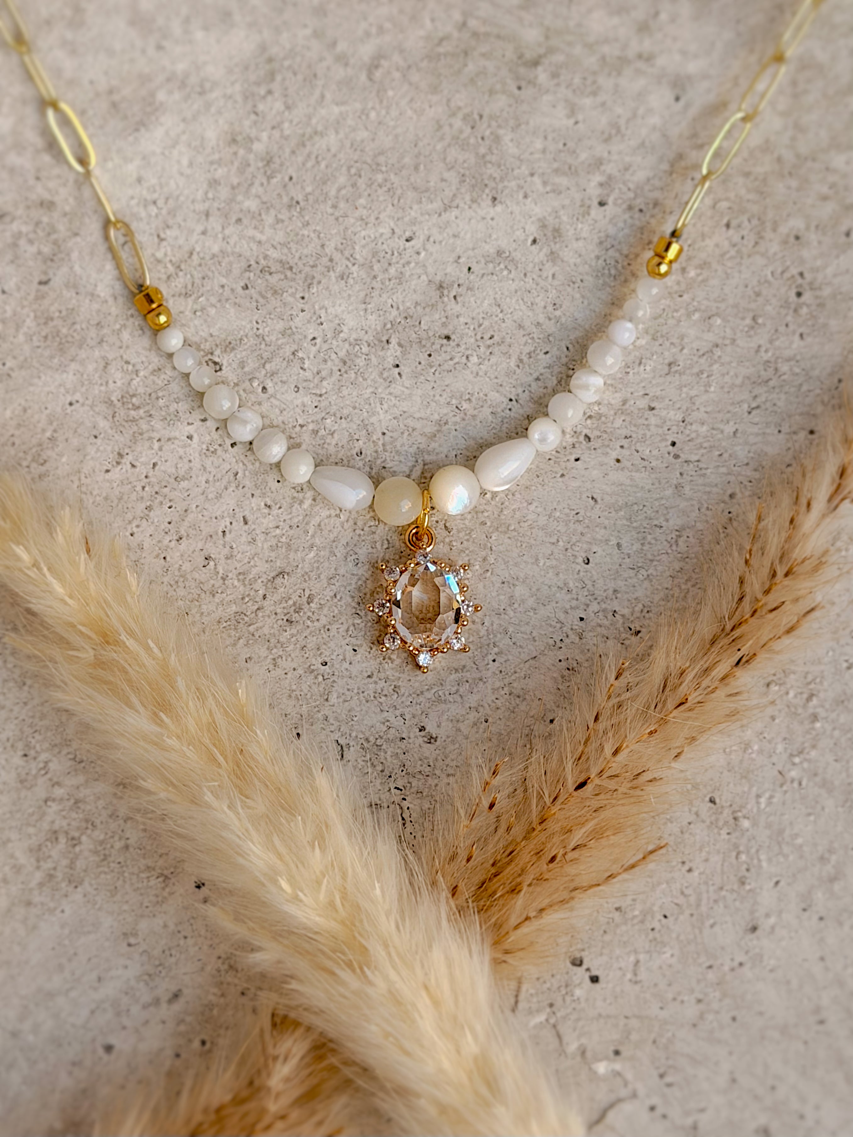 Handmade one-of-a-kind crystal beaded charm necklace featuring natural white gemstones, a faceted crystal centerpiece, and an 18-inch gold paperclip chain by Rising Soul Jewelry.