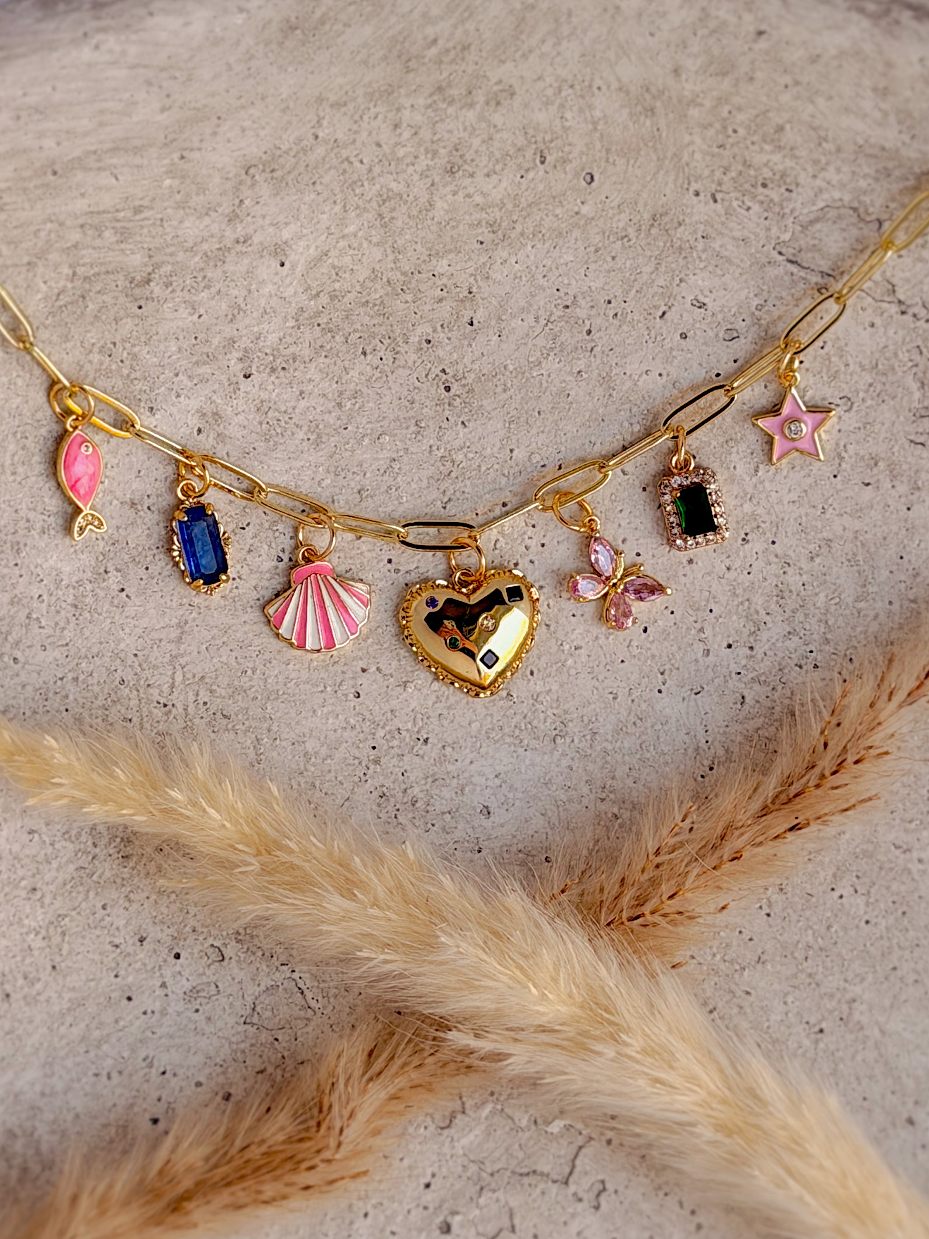 One of a Kind Heart Charm Necklace with colorful enamel shell, fish, and star charms, cubic zirconia butterfly, vibrant gemstone accents, and gold paperclip chain handcrafted by Rising Soul Jewelry.