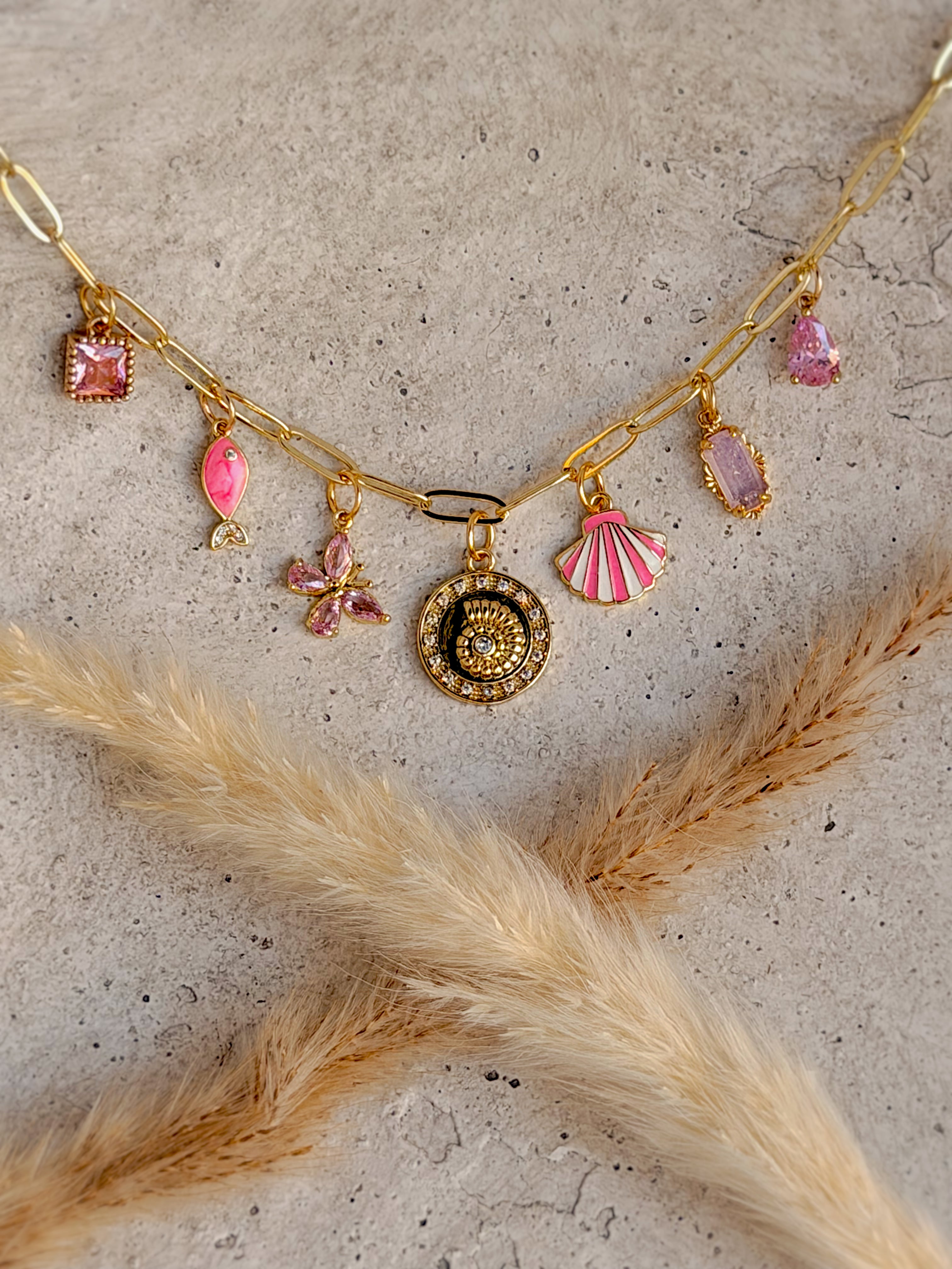 One of a Kind Pink Charm Necklace with enamel fish and shell charms, pink gemstone accents, cubic zirconia butterfly and vintage medallion charms, and gold paperclip chain handcrafted by Rising Soul Jewelry.