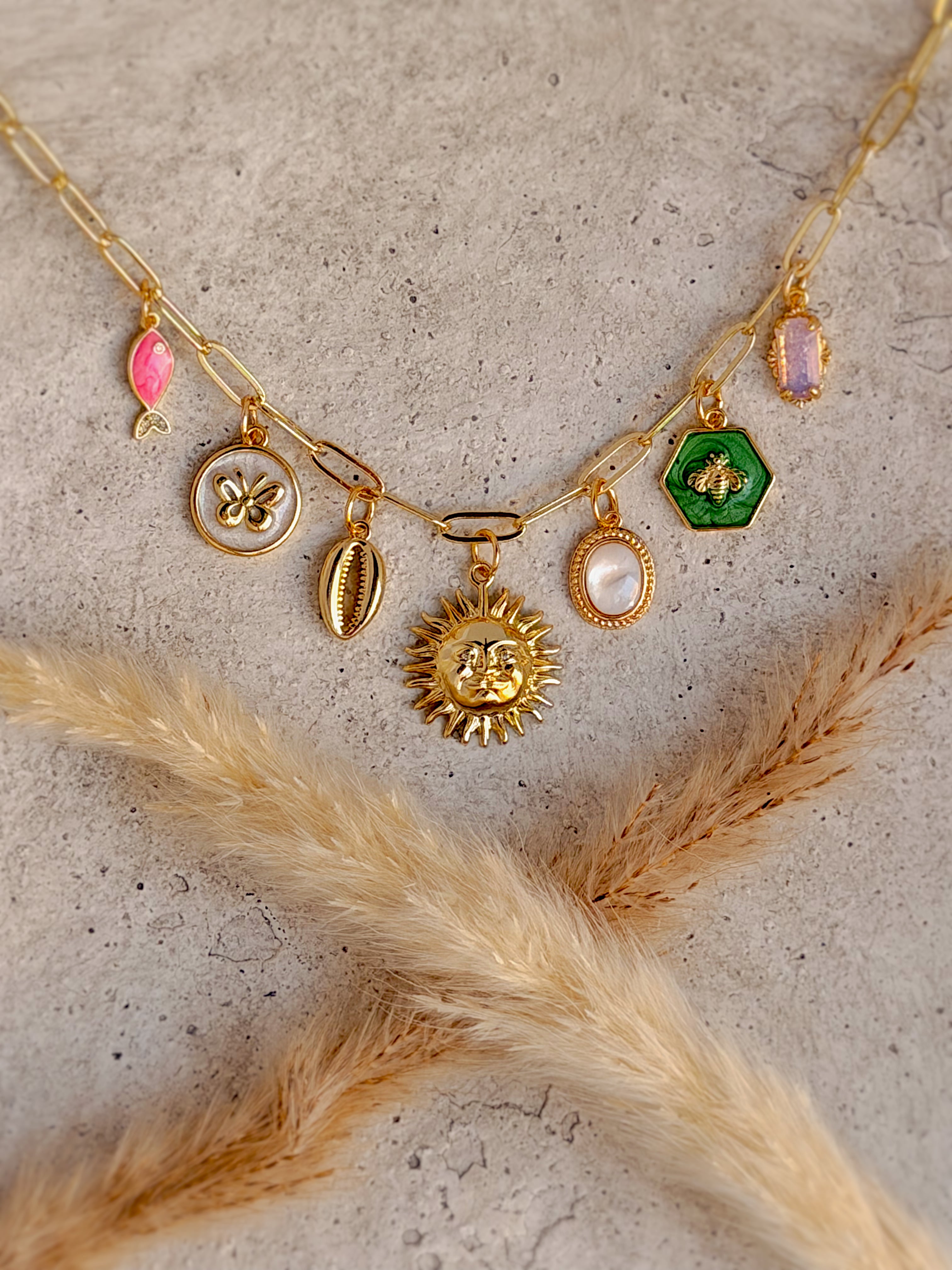 One of a Kind Sun Charm Necklace with genuine mother of pearl, enamel butterfly, bee, shell, and fish charms, gemstone accents, and gold paperclip chain handcrafted by Rising Soul Jewelry.