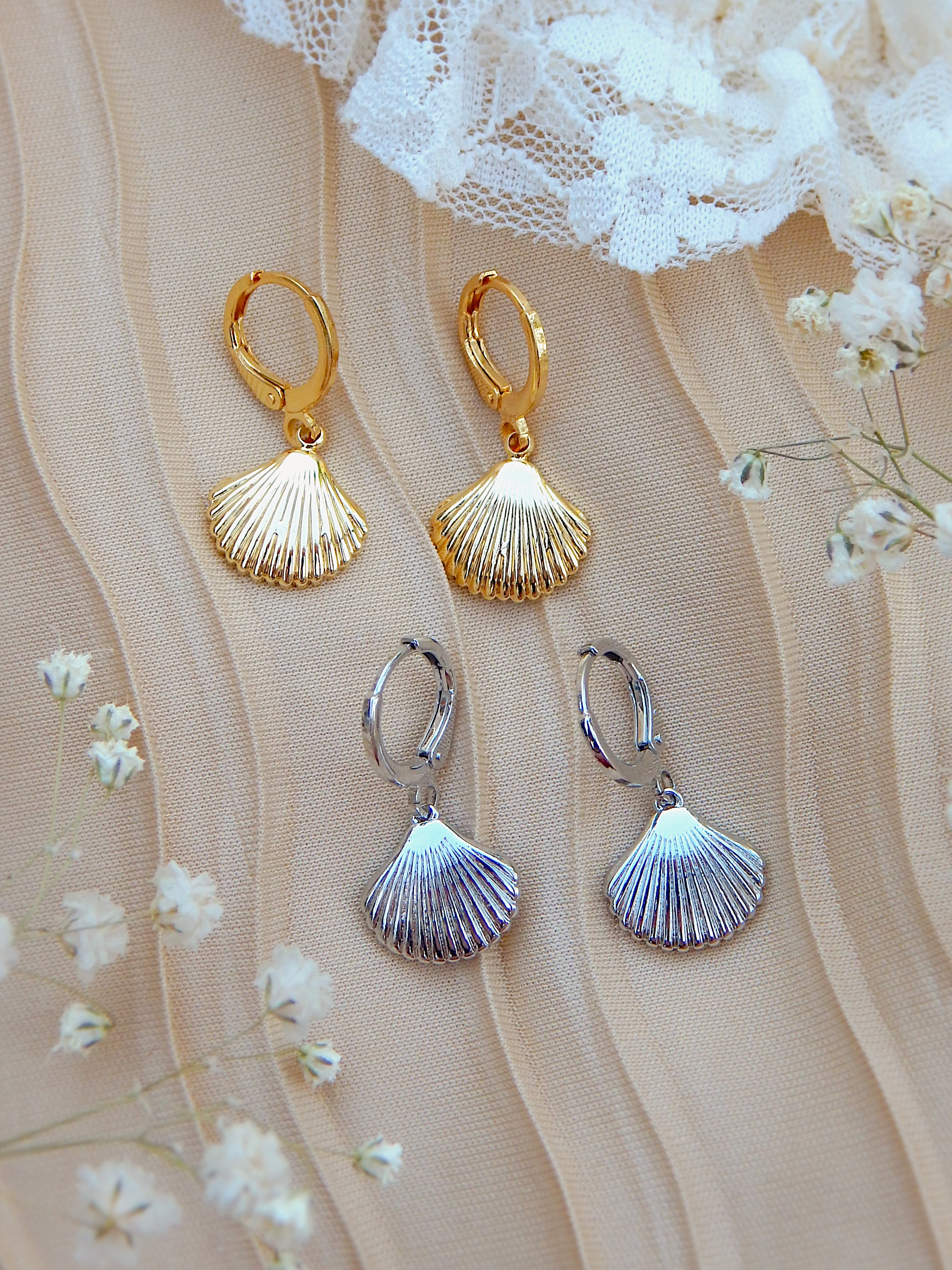 Gold and silver seashell huggie earrings displayed together, showing both color options in beach-inspired jewelry design