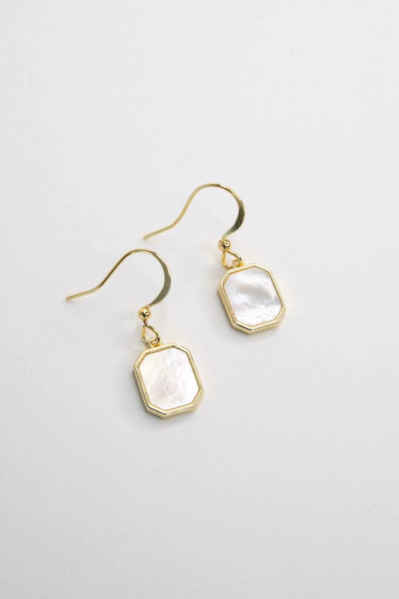 Gold octagon mother of pearl drop earrings on white background, minimal elegant jewelry product shot